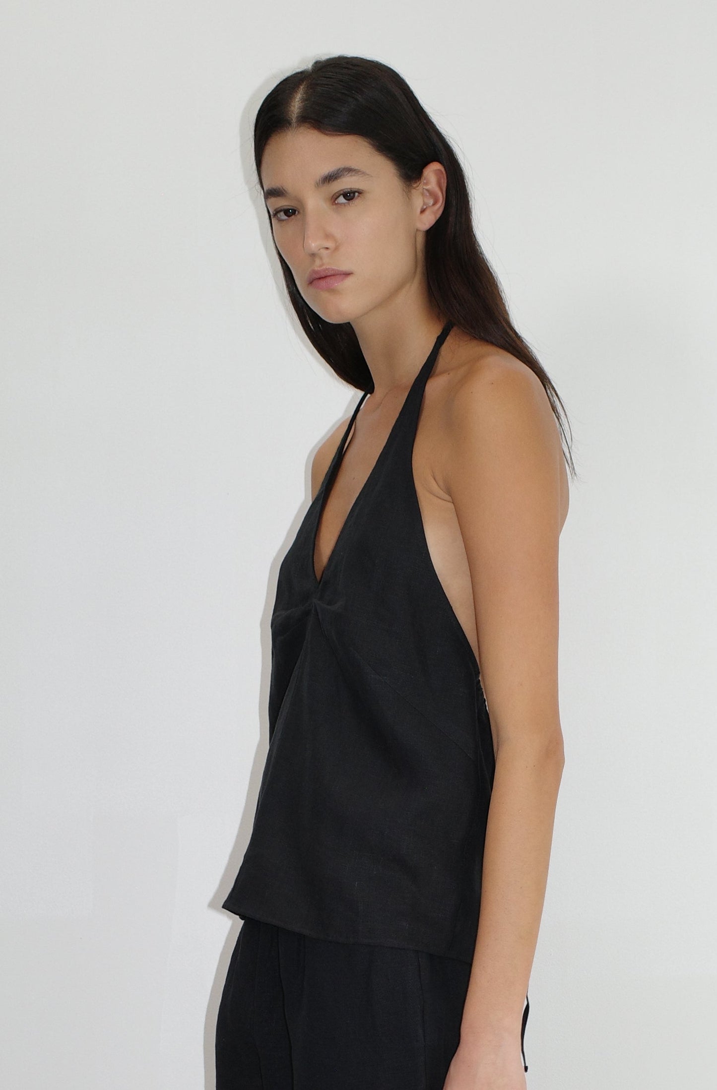 female model wears the linen ease trouser by Deiji Studios in black
the ankle length pant features a soft minimal elastic waist with side seam pockets in a straight leg
can be worn at home, in bed, or out
made from 100% GOTS certified organic, OEKO-TEX 100 certified and EU certified stone washed french linen
paired with a black linen halter top