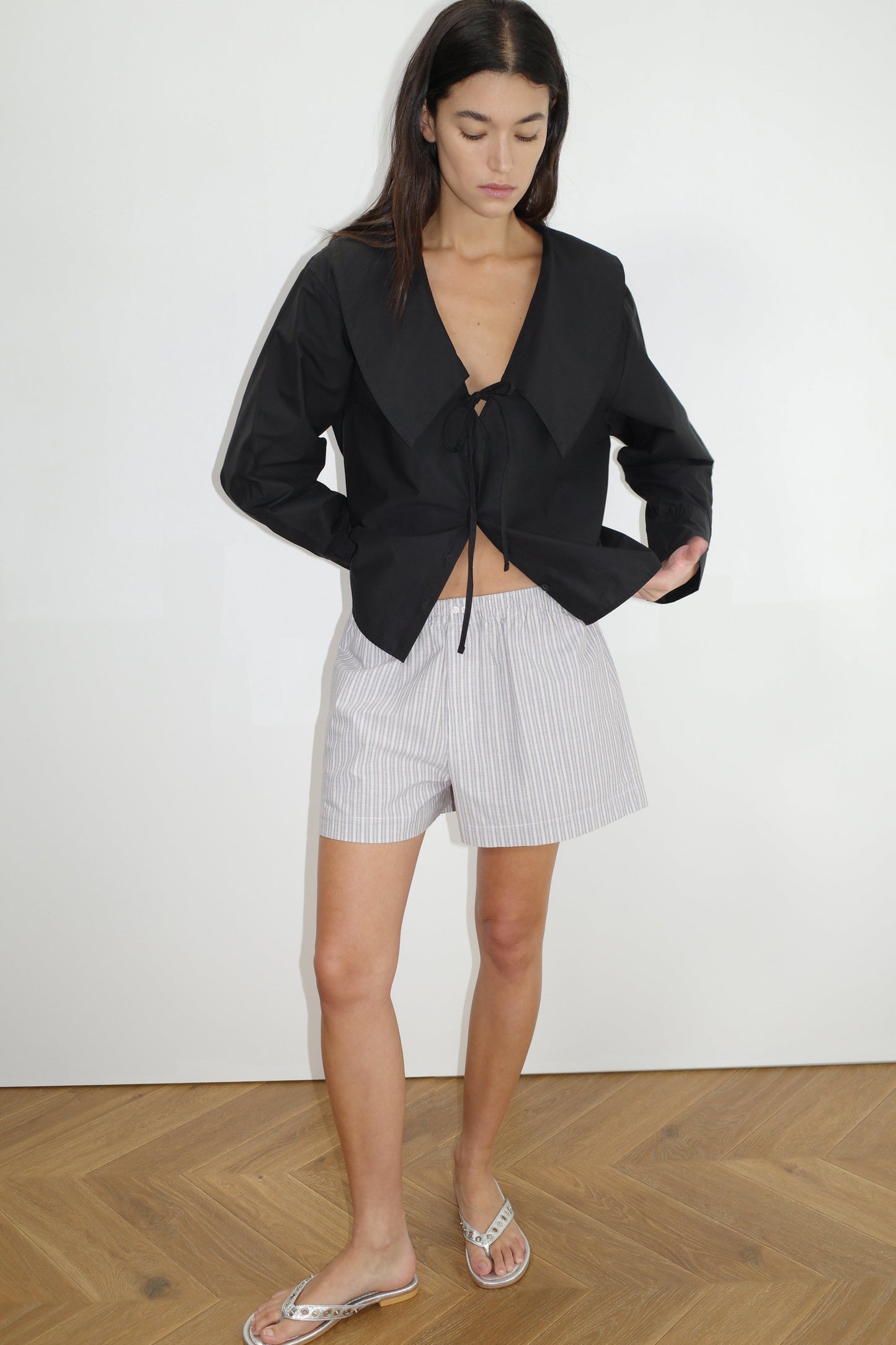 the collared tie shirt by Deiji Studios in black
a structured shirt features an oversized collar and cuff, tie at front collar opening, dropped shoulder and elongated sleeves in a boxy fit
made from 100% GOTS certified organic cotton poplin
paired with a blue stripe cotton boxer