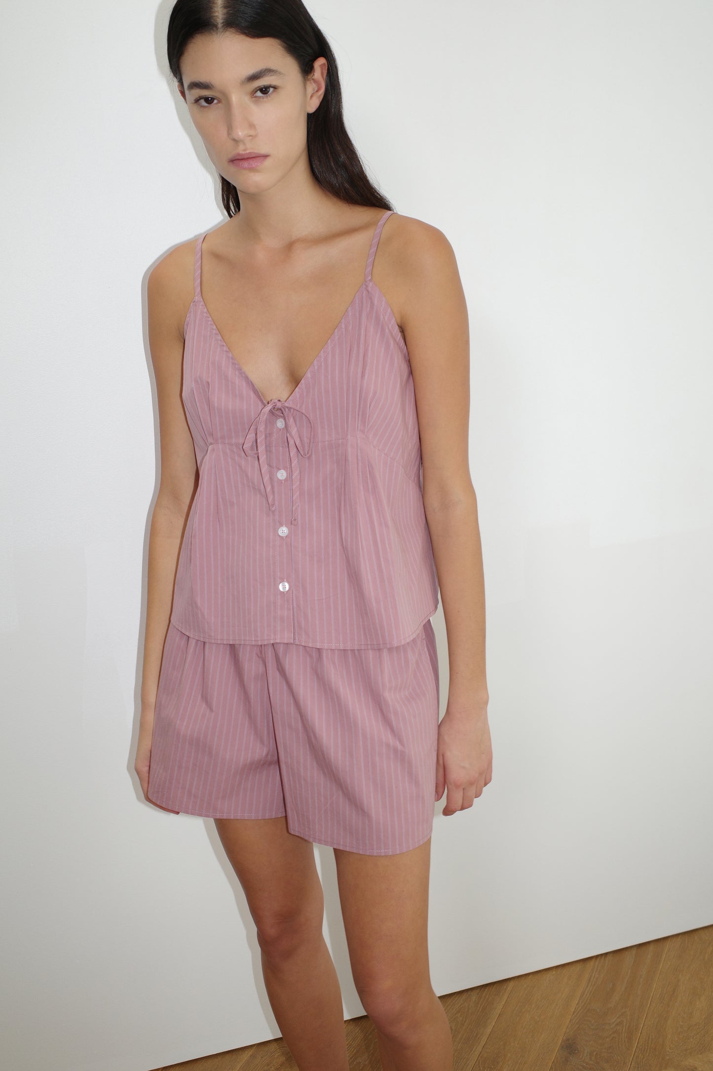female model wears the placket short set by Deiji Studios in salt stripe
a lightweight everyday top features a flattering v neckline, button down front, side fold pleat detail at bust with a self-fabric tie pairs back with an easy pull on short, featuring a soft elastic waist and side seam pockets to wear as a set or separately
made from 100% organic cotton poplin