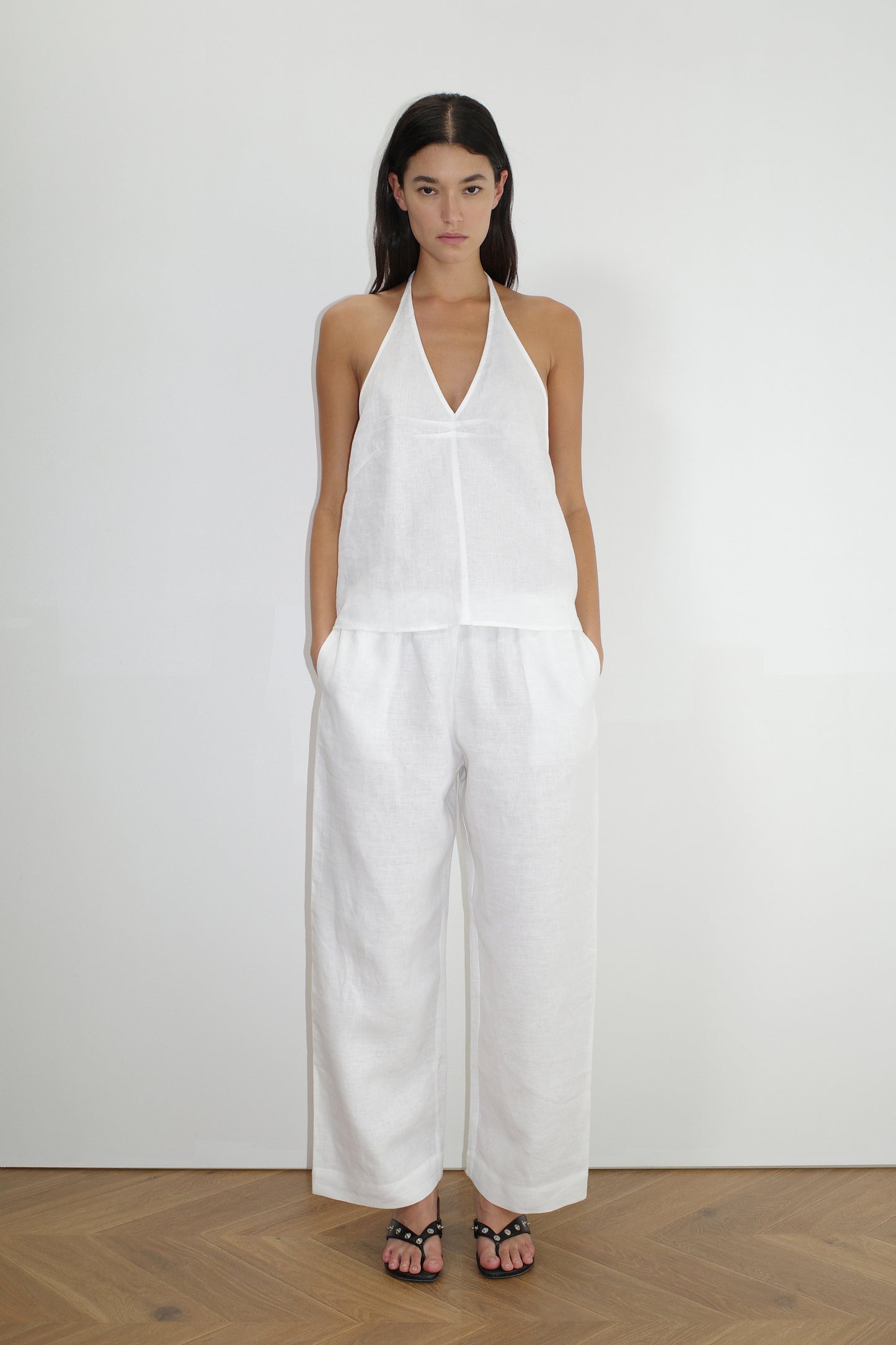 female model wears the linen ease trouser by Deiji Studios in white
the ankle length pant features a soft minimal elastic waist with side seam pockets in a straight leg
can be worn at home, in bed, or out
made from 100% GOTS certified organic, OEKO-TEX 100 certified and EU certified stone washed french linen
paired with a white linen halter top