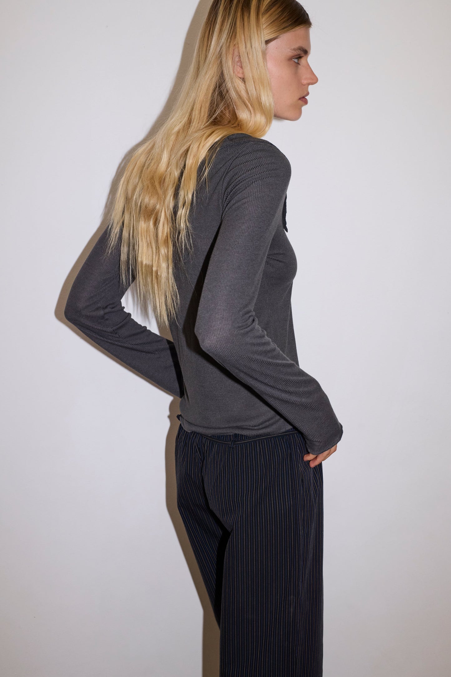 blonde female model wears grey long sleeve top, worn with a navy and yellow striped trouser
