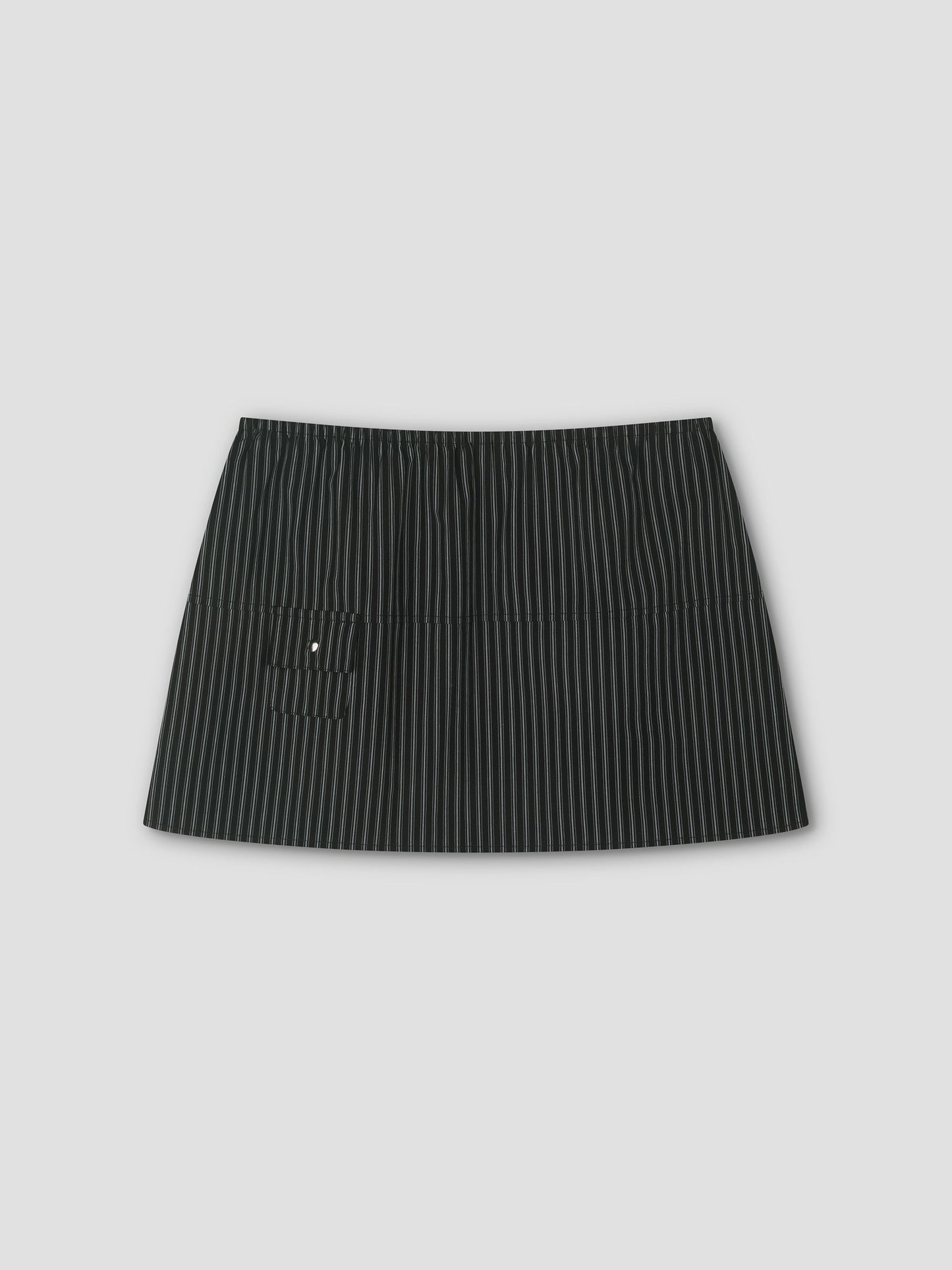 The Pocket Skirt - Mono Stripe is a black mini skirt with thin white pinstripes, an elastic waistband, and a small left front pocket, shown against a plain light gray background.