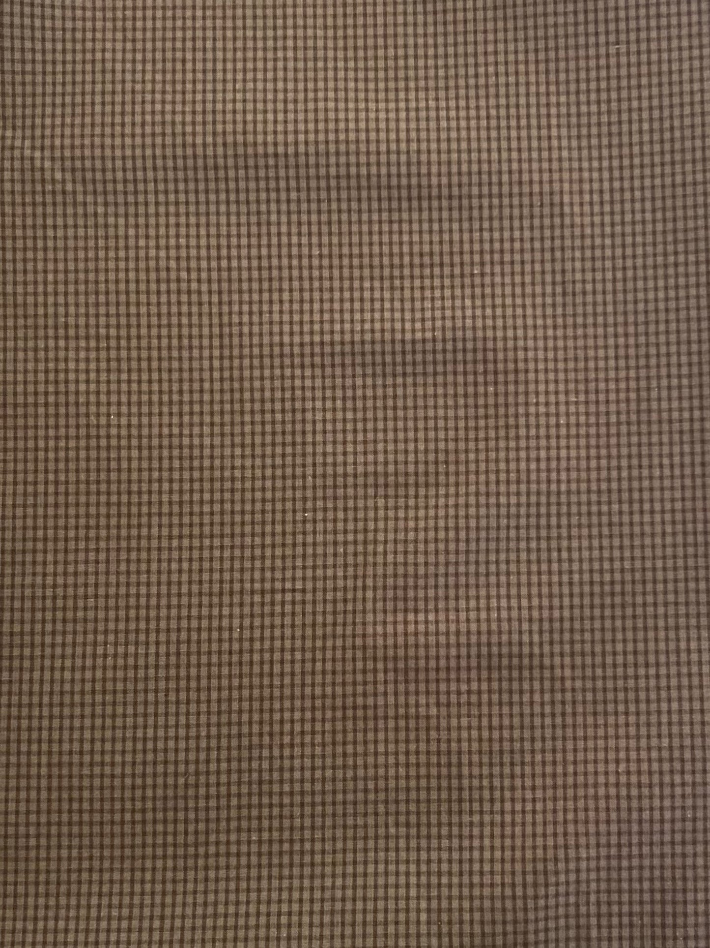The Button Dress - Carob Check features organic cotton fabric in a brown grid pattern, with a subtle, blurred human face impression that blends seamlessly into the background.