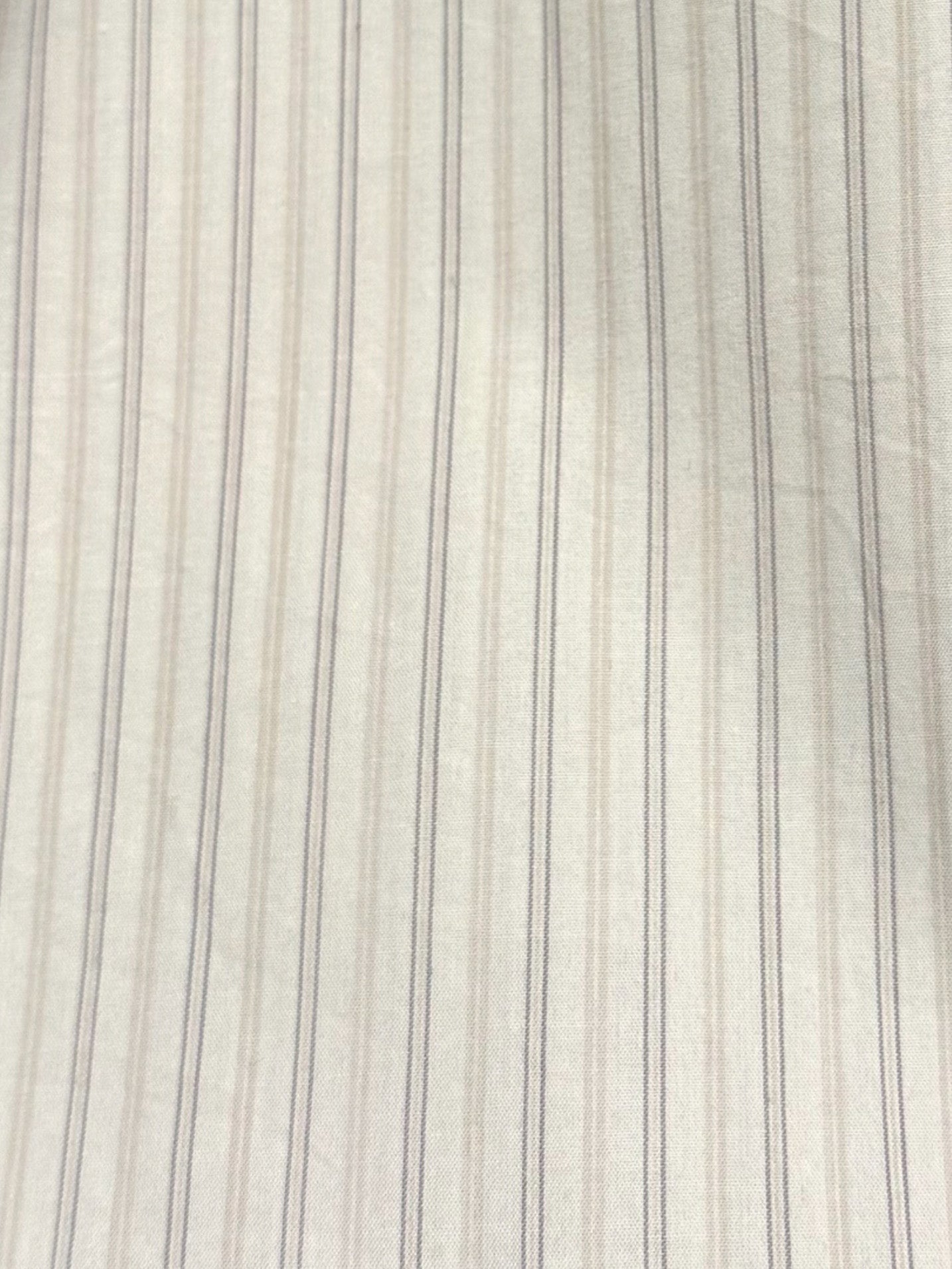 Close-up of the Button Skirt - Pacific Stripe, featuring white fabric with subtle beige and gray vertical stripes. This lightweight woven textile has a delicate ticking stripe pattern and a naturally soft, slightly wrinkled texture.