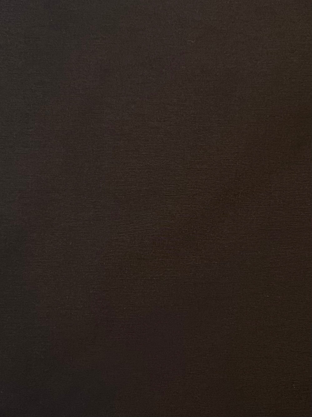 A plain, solid dark brown textured surface fills the image, evoking the rich tone of the Press Stud Jacket - Dark Chocolate by Deiji Studios, with no visible patterns or objects.