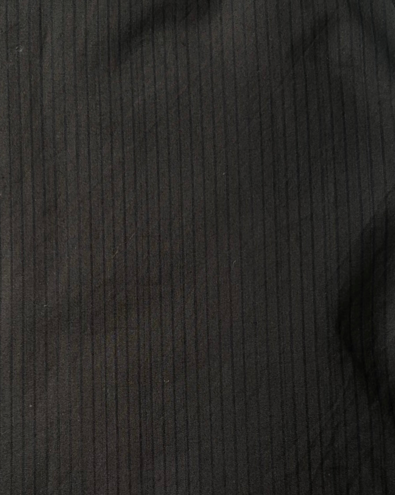 Close-up of the Layered Top - Black Stripe by Deiji Studios in dark organic cotton with subtle vertical pinstripes and soft, uneven shadows.