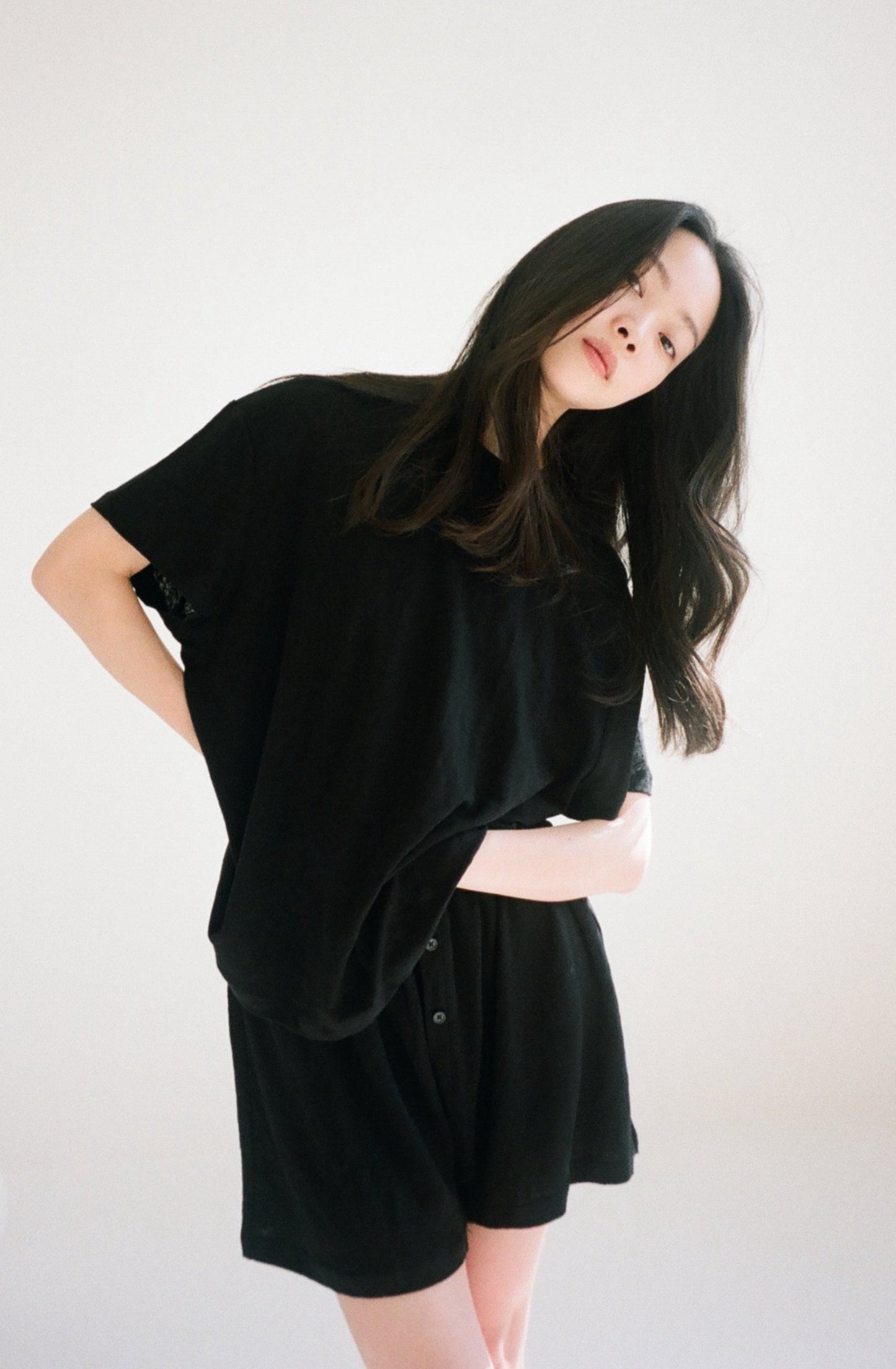 Female model wearing soft t shirt - black by Deiji Studios against plain background