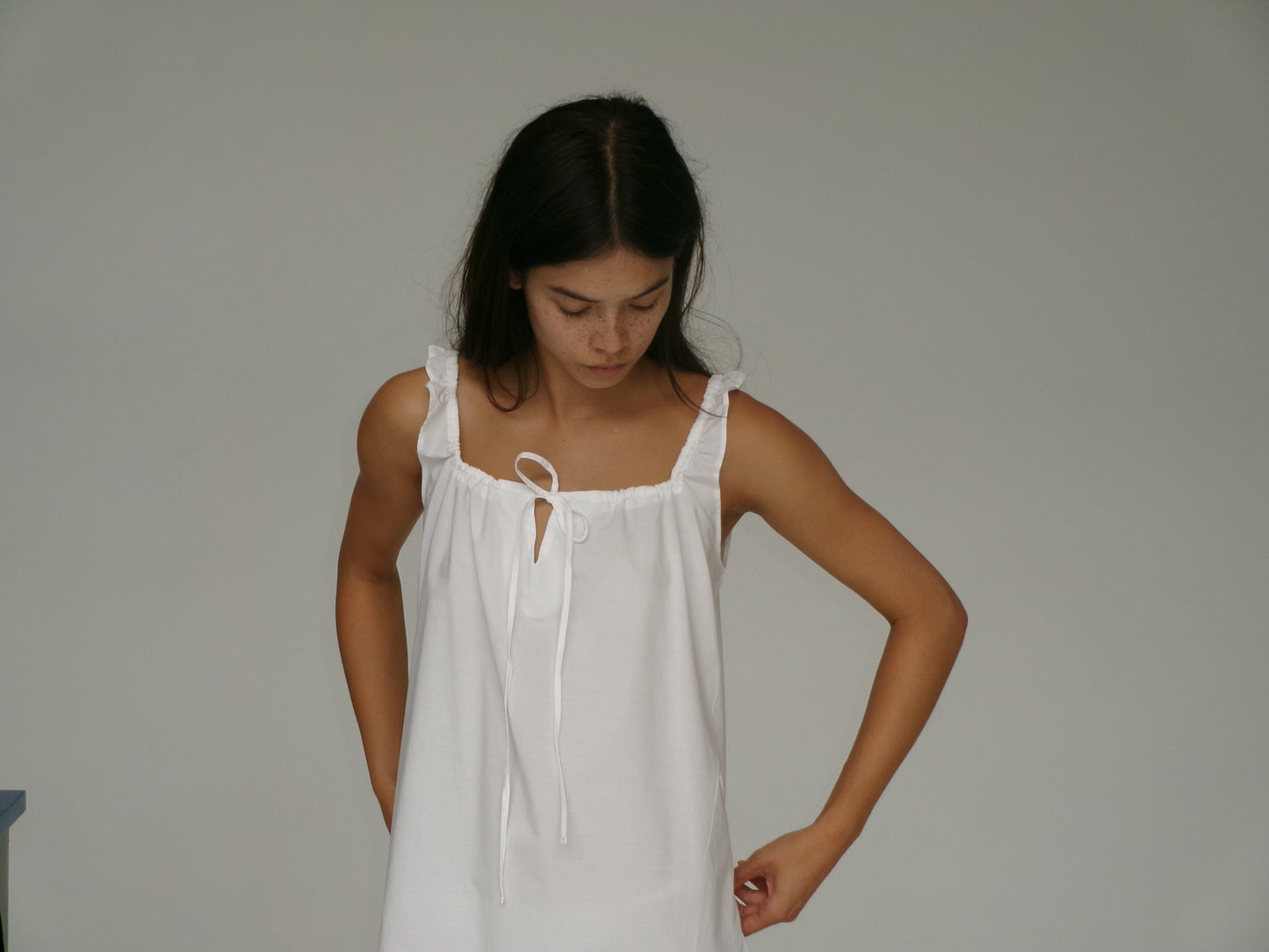 female model wears the paper dress by Deiji Studios in white, a crisp and lightweight maxi-length dress features a flattering gathered square neckline with keyhole and tie front feature and side seam pockets, made from GOTS certified organic cotton poplin