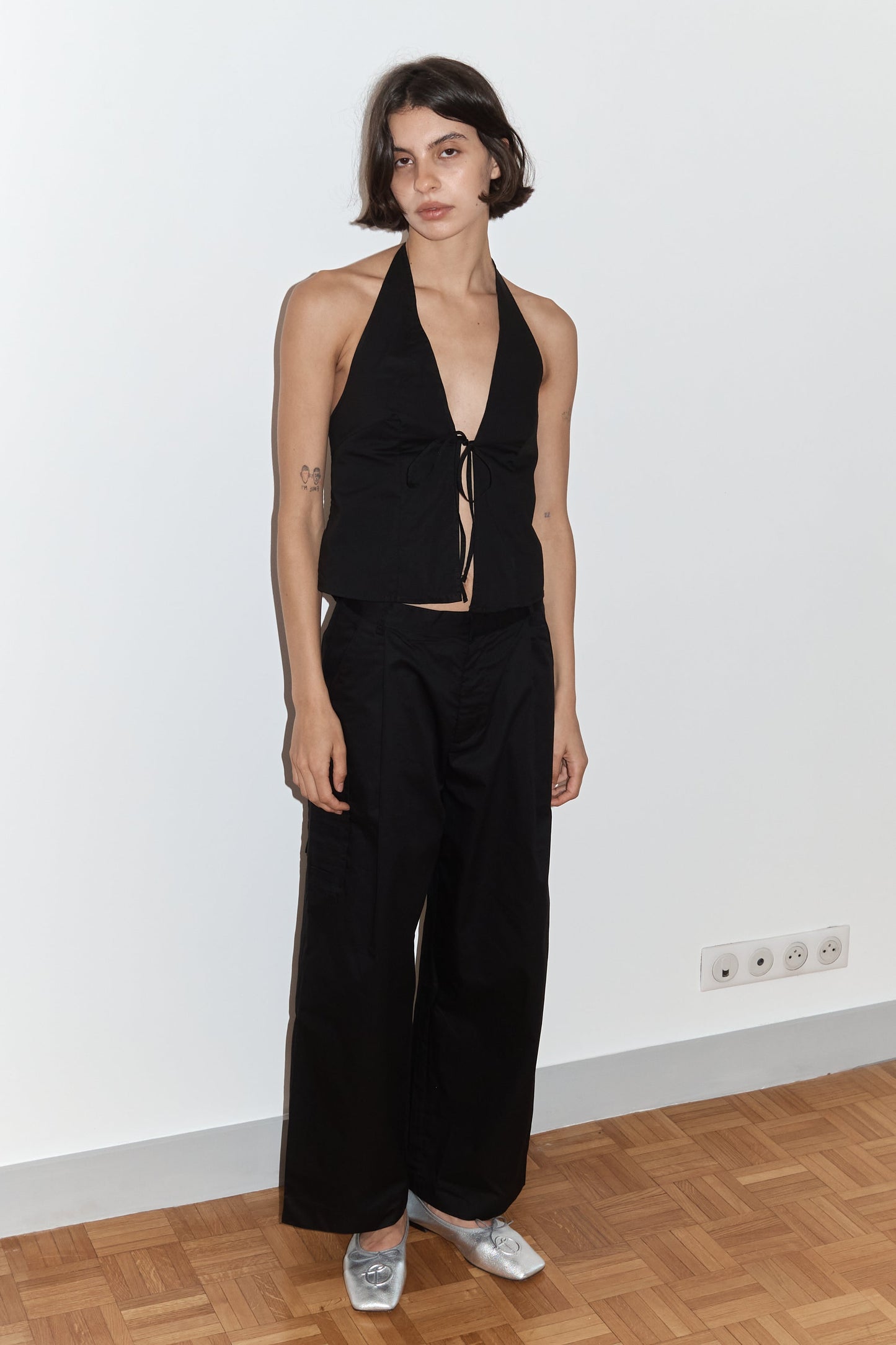 female model wears the open halter top top by Deiji Studios in black

top features open front with centre bust tie, halterneck tie and v neckline, bust seams for subtle shaping and shirred back

made from 100% GOTS certified organic cotton poplin

paired with a black cotton trouser
