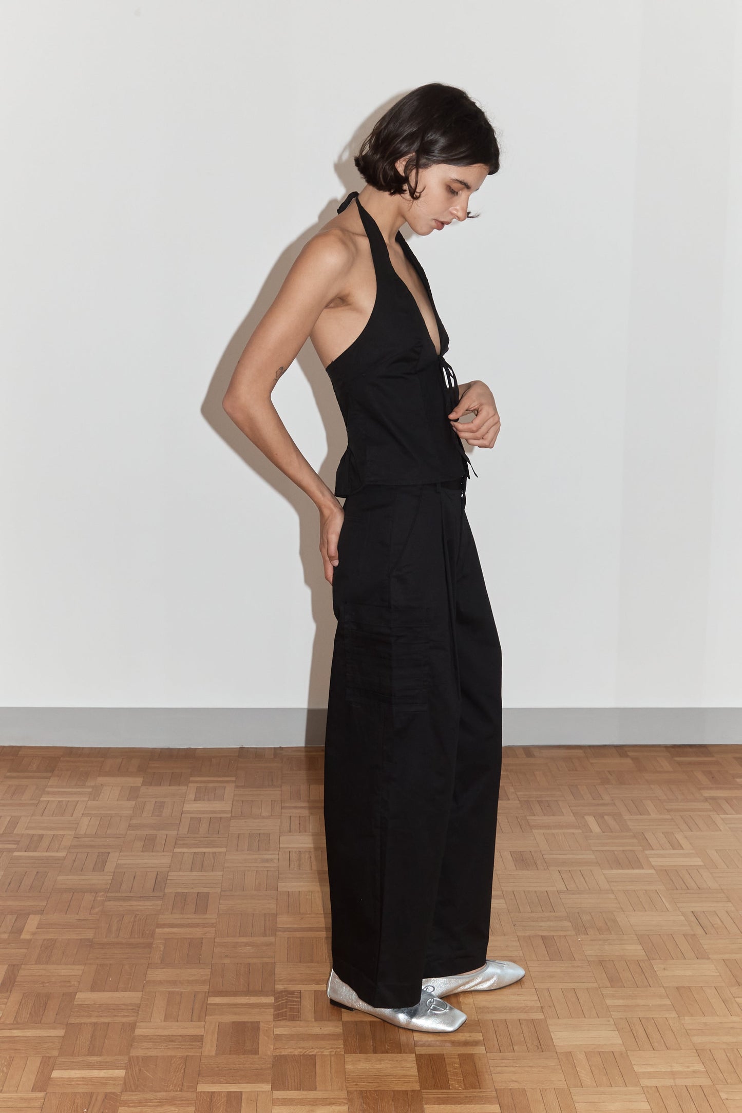 female model wears the open halter top top by Deiji Studios in black

top features open front with centre bust tie, halterneck tie and v neckline, bust seams for subtle shaping and shirred back

made from 100% GOTS certified organic cotton poplin

paired with a black cotton trouser