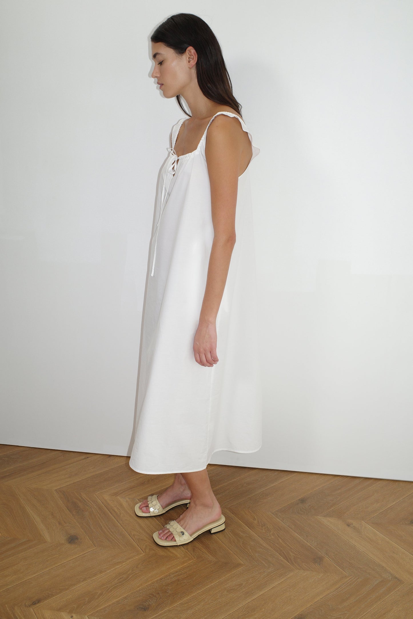 female model wears the paper dress by Deiji Studios in white, a crisp and lightweight maxi-length dress features a flattering gathered square neckline with keyhole and tie front feature and side seam pockets, made from GOTS certified organic cotton poplin
