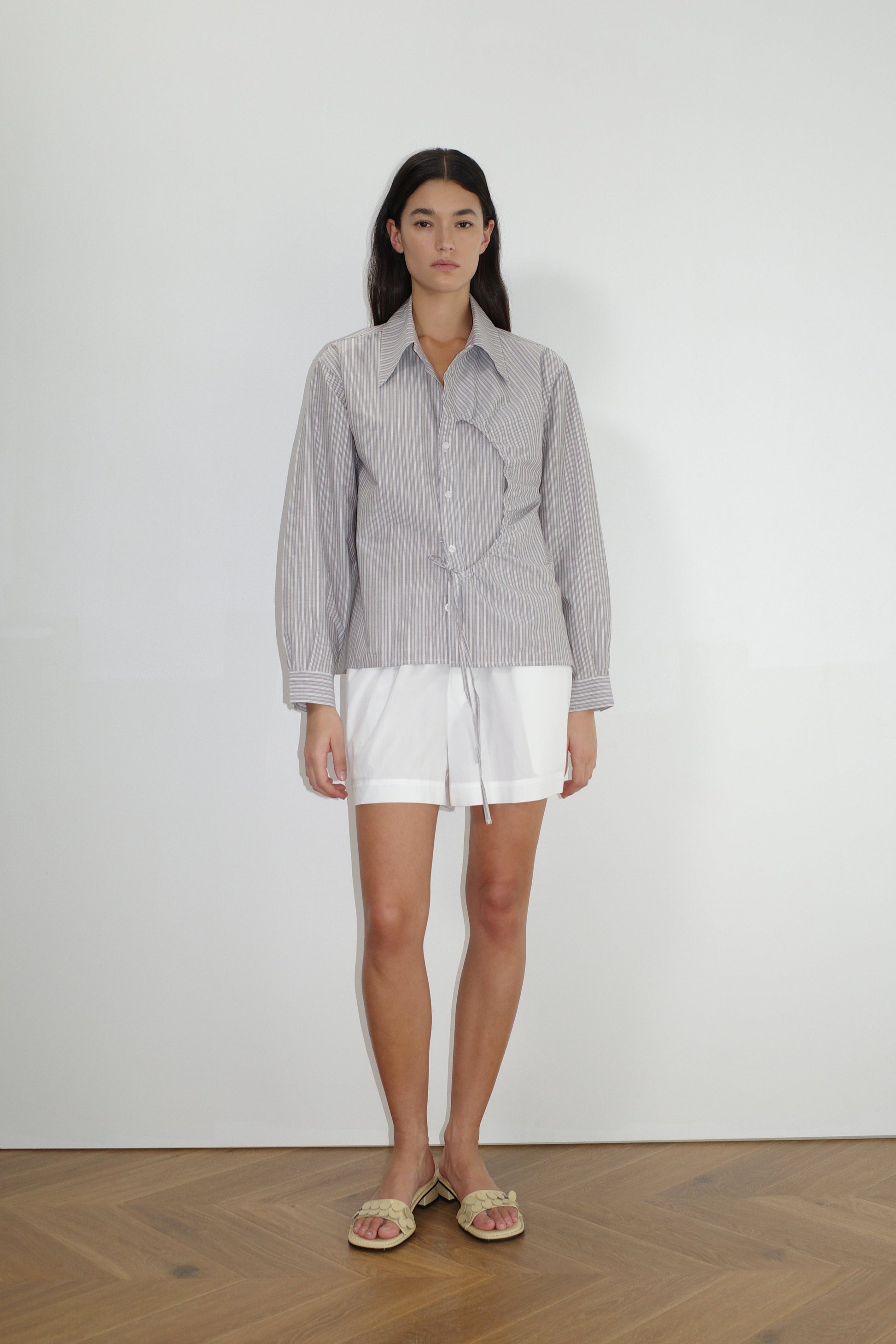 female model wears the arch tie shirt by Deiji Studios in seas stripe


a classic crisp button up shirt in a boxy fit, featuring a dropped back yoke, dropped shoulders, a classic shirting cuff with a layered arch fabric detail on front with tie


made from 100% GOTS certified organic cotton poplin

paired with a white cotton short