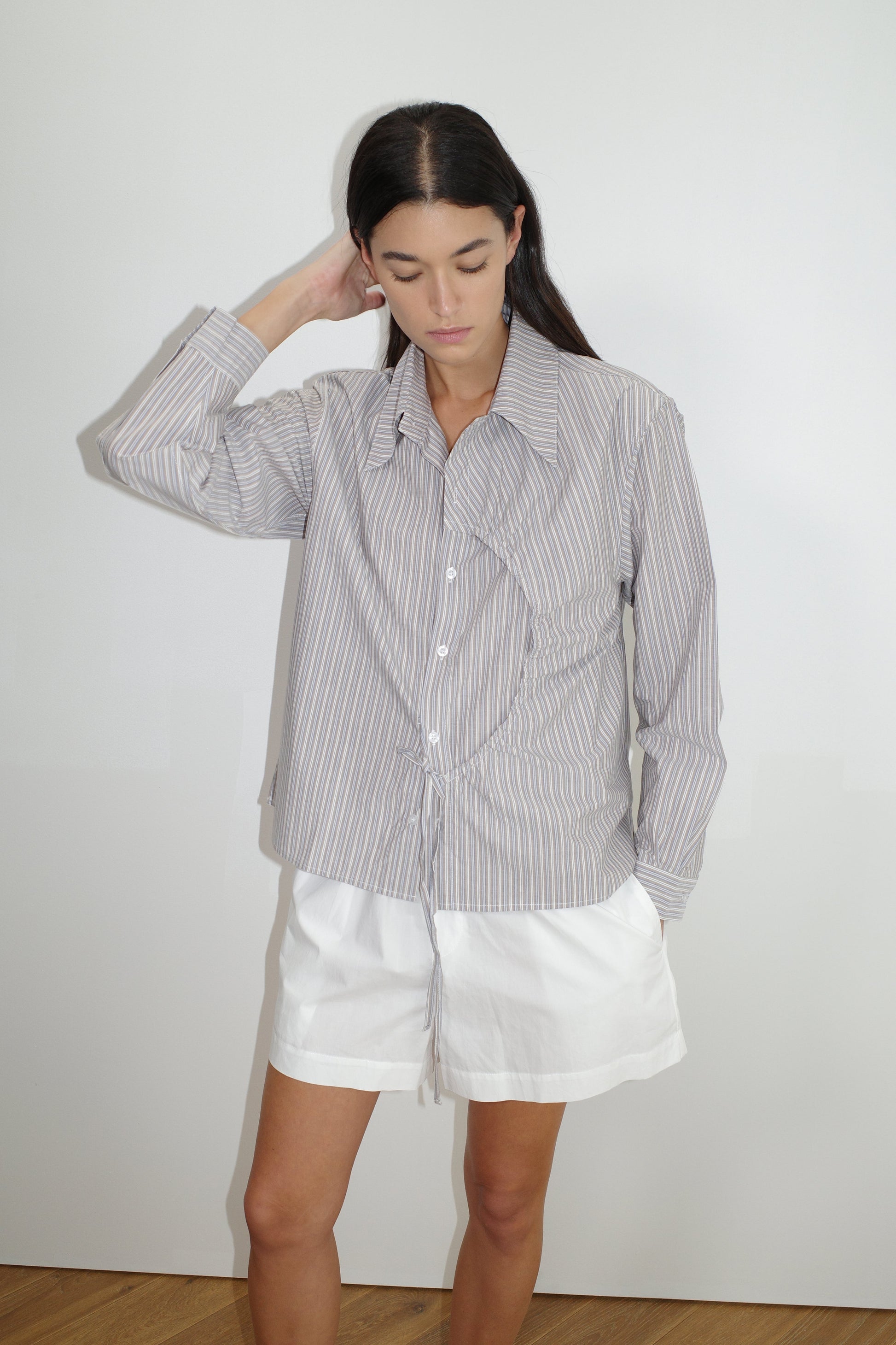 female model wears the arch tie shirt by Deiji Studios in seas stripe


a classic crisp button up shirt in a boxy fit, featuring a dropped back yoke, dropped shoulders, a classic shirting cuff with a layered arch fabric detail on front with tie


made from 100% GOTS certified organic cotton poplin

paired with a white cotton short