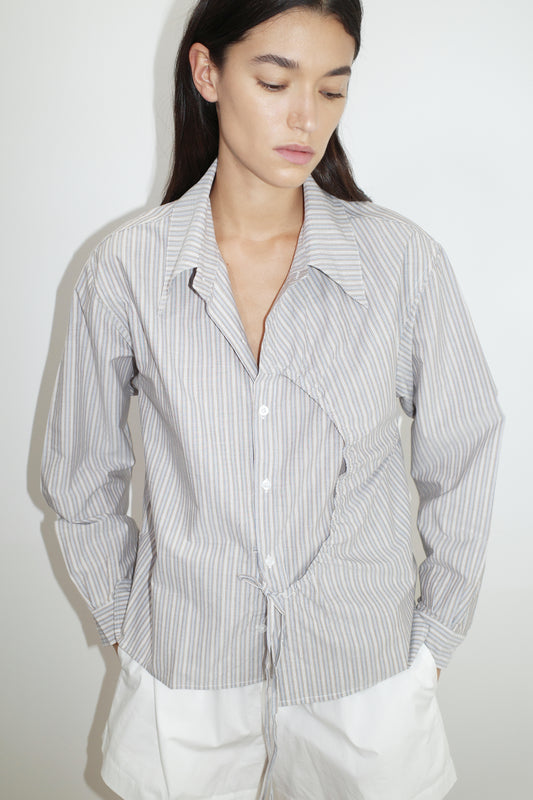 female model wears the arch tie shirt by Deiji Studios in seas stripe


a classic crisp button up shirt in a boxy fit, featuring a dropped back yoke, dropped shoulders, a classic shirting cuff with a layered arch fabric detail on front with tie


made from 100% GOTS certified organic cotton poplin

paired with a white cotton short