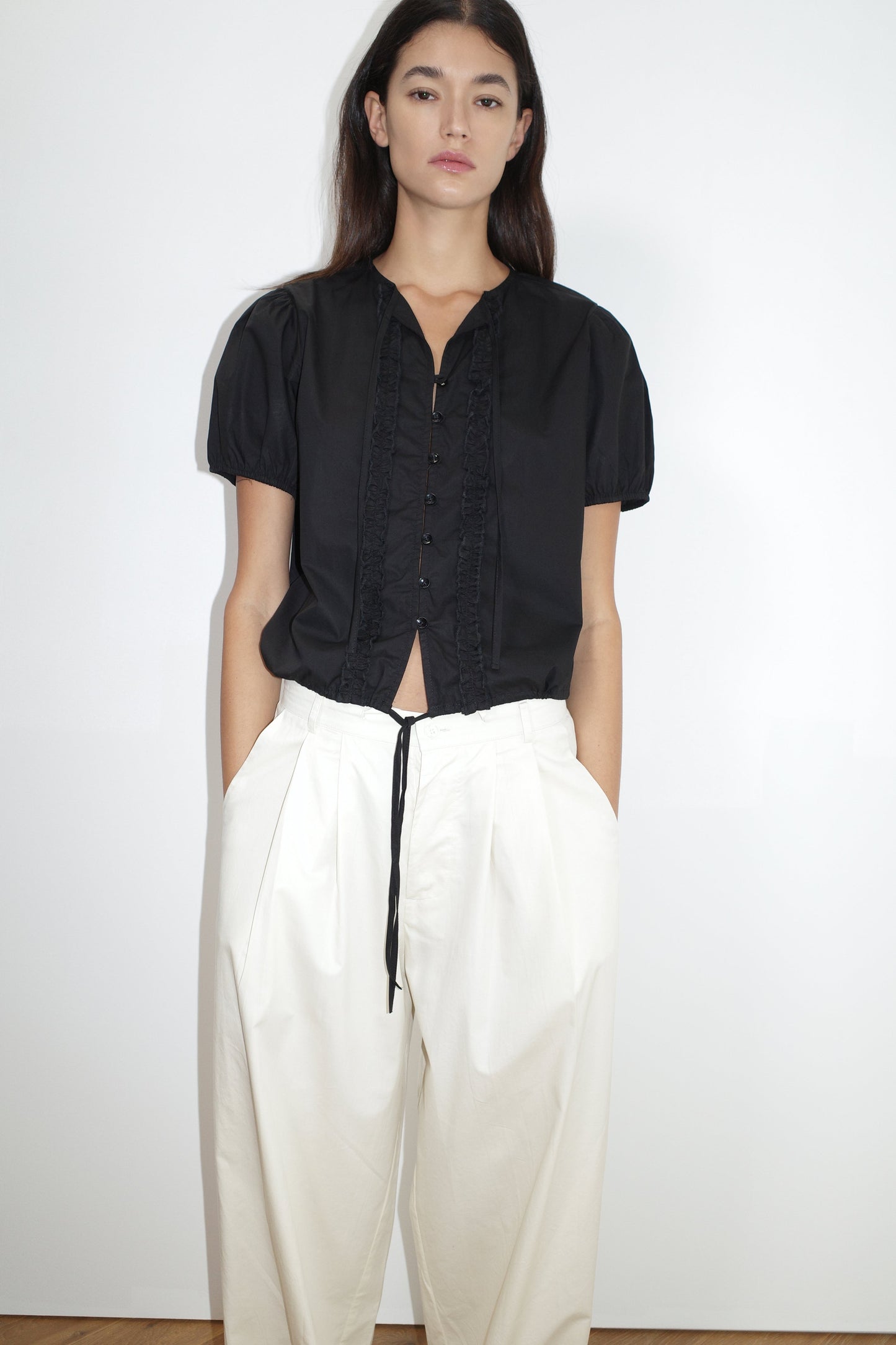 female model wears the double frill top by Deiji Studios in black


elevated everyday top features a flattering v neckline with button down front, fixed ruffle details, soft bloussant sleeve and gathered elastic cuffs


made from 100% GOTS certified organic cotton poplin

paired with a white cotton trouser