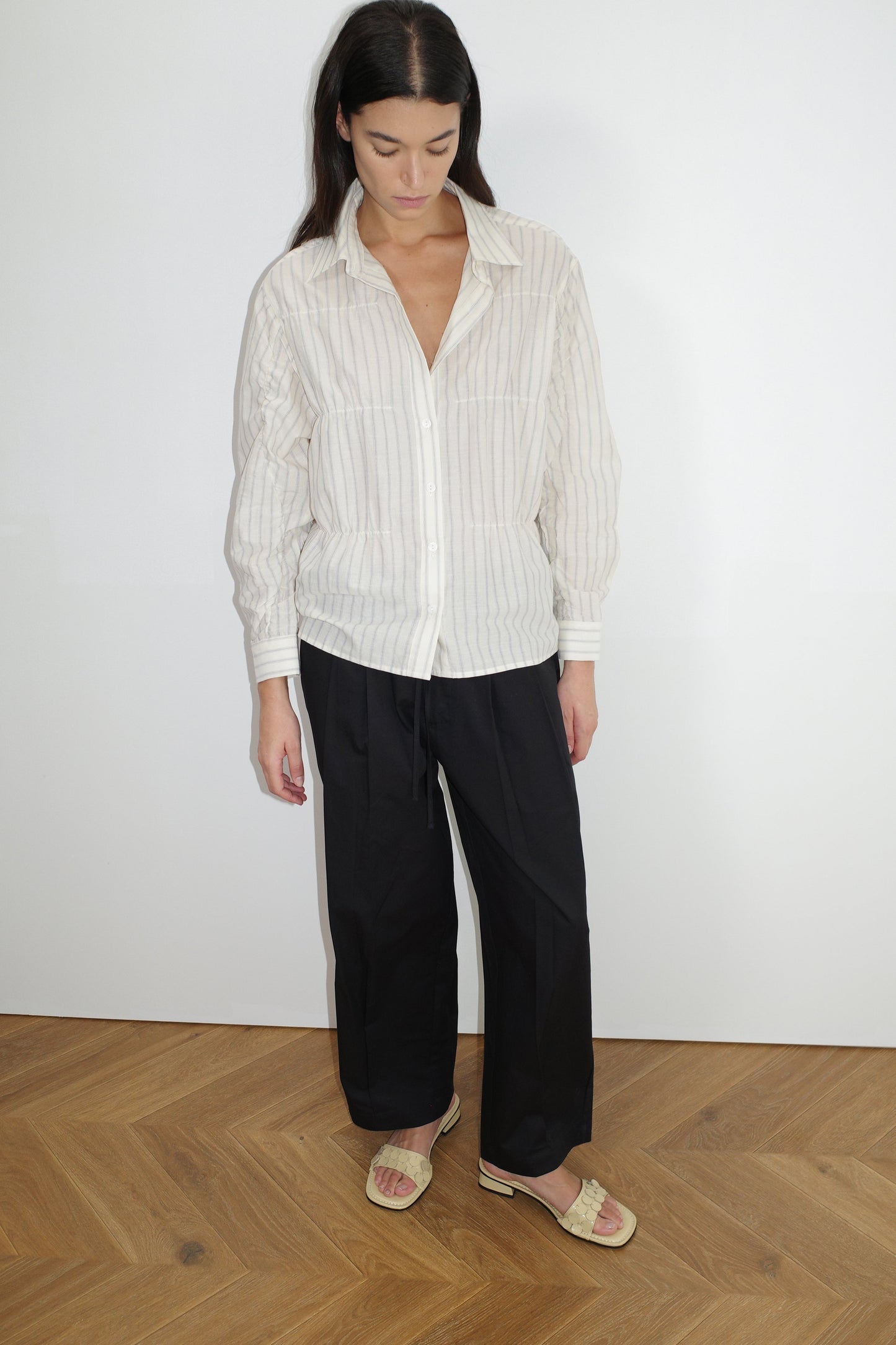 female model wears the gathered shirt by Deiji Studios in raquette stripe


a classic button up style shirt featuring a butter base with mixed blue stripe, elasticated gathered seams and dropped shoulder for a relaxed fit


made from 100% GOTS organic cotton

paired with a black pant