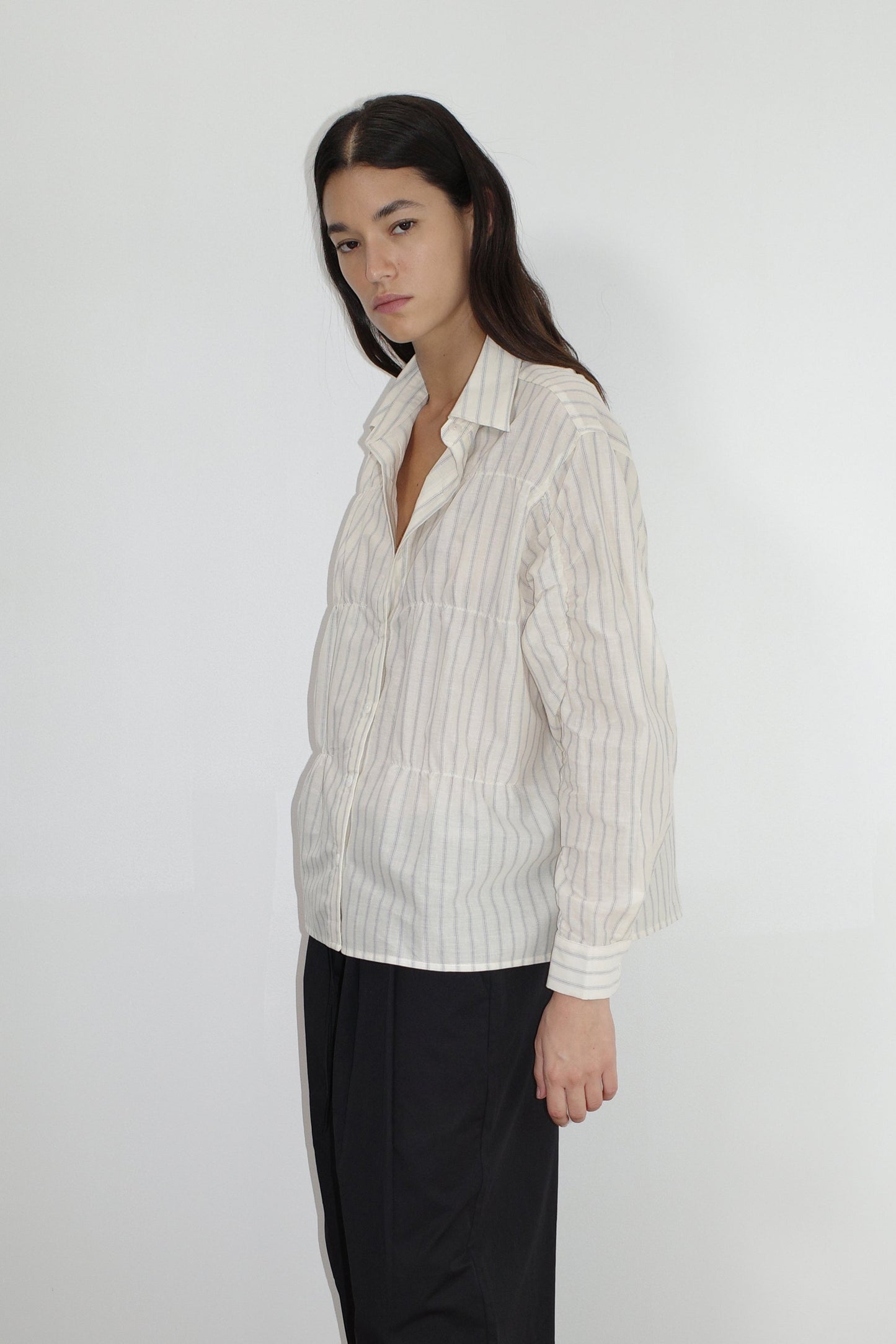 female model wears the gathered shirt by Deiji Studios in raquette stripe


a classic button up style shirt featuring a butter base with mixed blue stripe, elasticated gathered seams and dropped shoulder for a relaxed fit


made from 100% GOTS organic cotton

paired with a black pant