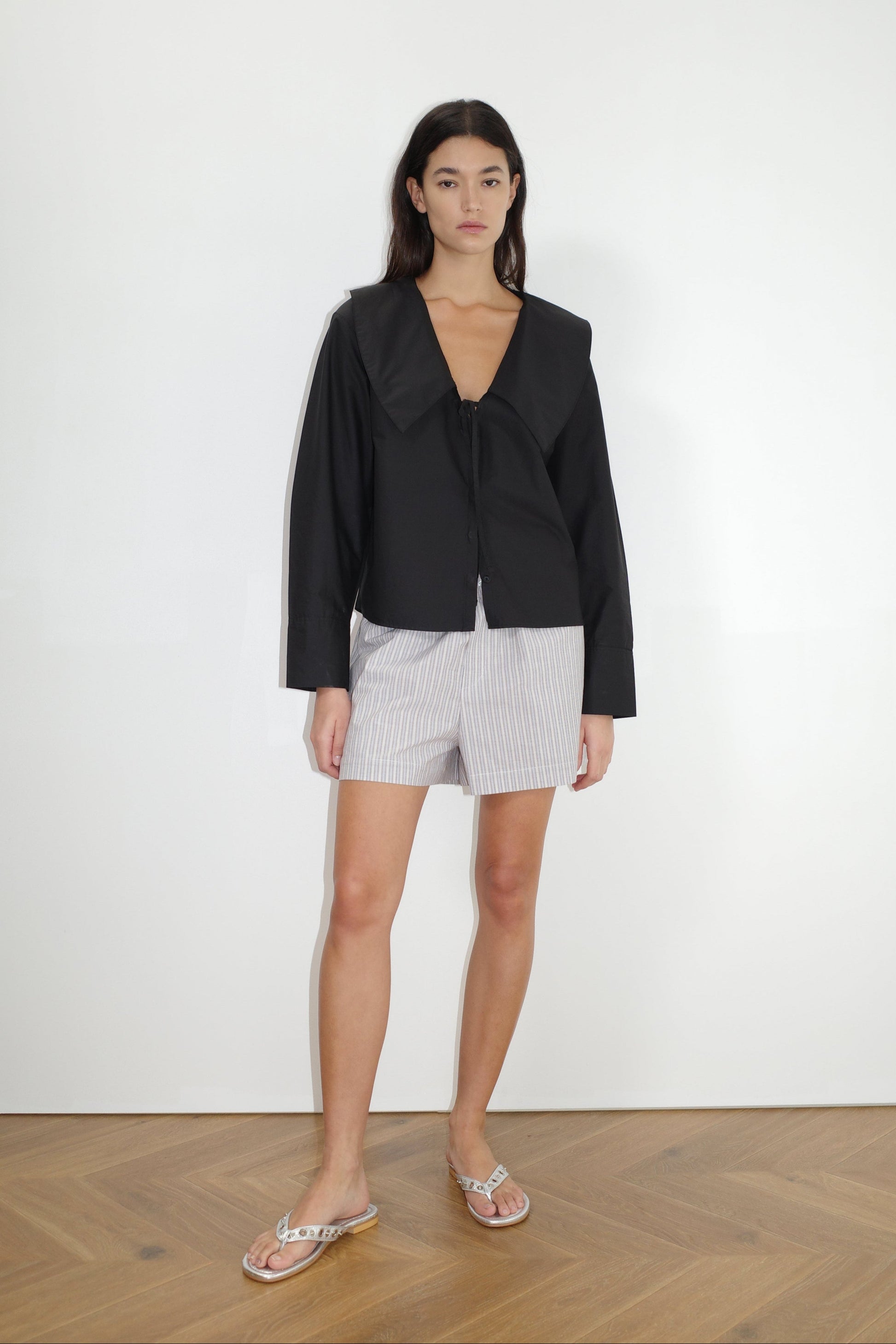the collared tie shirt by Deiji Studios in black


a structured shirt features an oversized collar and cuff, tie at front collar opening, dropped shoulder and elongated sleeves in a boxy fit


made from 100% GOTS certified organic cotton poplin

paired with a blue stripe cotton boxer