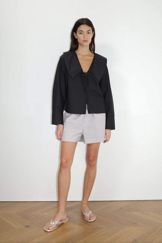 the collared tie shirt by Deiji Studios in black


a structured shirt features an oversized collar and cuff, tie at front collar opening, dropped shoulder and elongated sleeves in a boxy fit


made from 100% GOTS certified organic cotton poplin

paired with a blue stripe cotton boxer