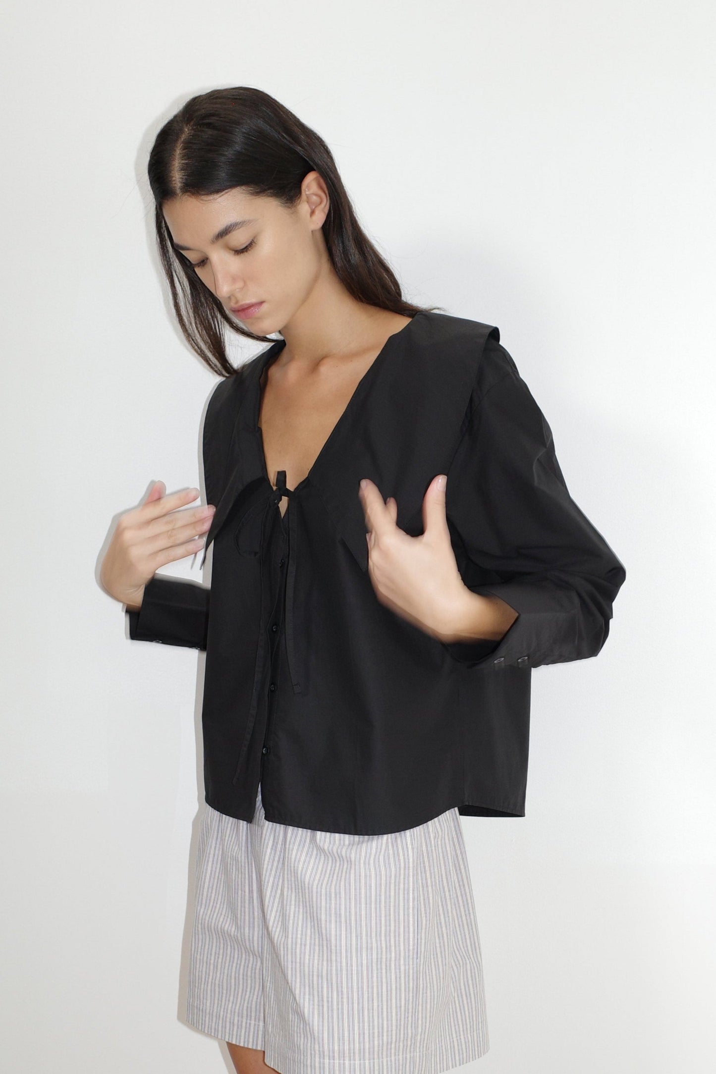 the collared tie shirt by Deiji Studios in black


a structured shirt features an oversized collar and cuff, tie at front collar opening, dropped shoulder and elongated sleeves in a boxy fit


made from 100% GOTS certified organic cotton poplin

paired with a blue stripe cotton boxer