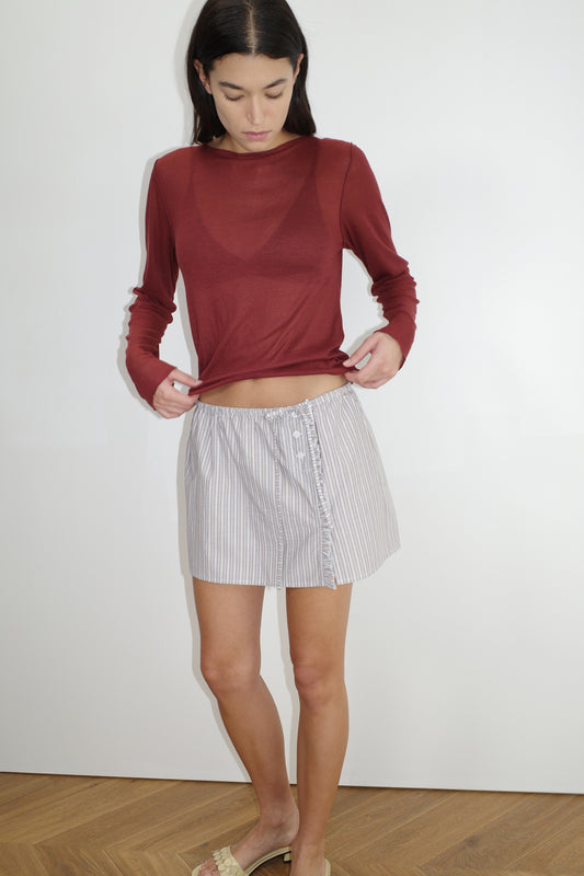 female model wears the ruffle mini skirt by Deiji Studios in seas stripe


simple mini skirt designed to sit at low waist features adjustable tie and ruffle edge on side with button detail


made from 100% GOTS certified organic cotton poplin

paired with a sheer knit long sleeve in crimson red