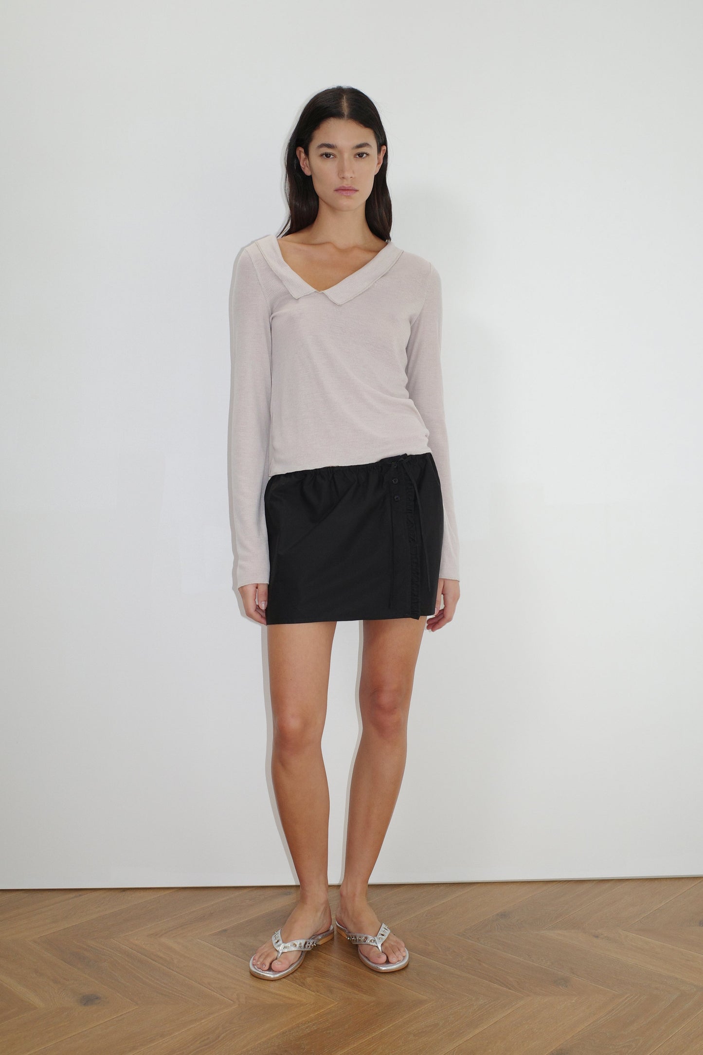 female model wears the ruffle mini skirt by Deiji Studios in black


simple mini skirt designed to sit at low waist features adjustable tie and ruffle edge on side with button detail


made from 100% GOTS certified organic cotton poplin

paired with a sheer knit long sleeve in beige