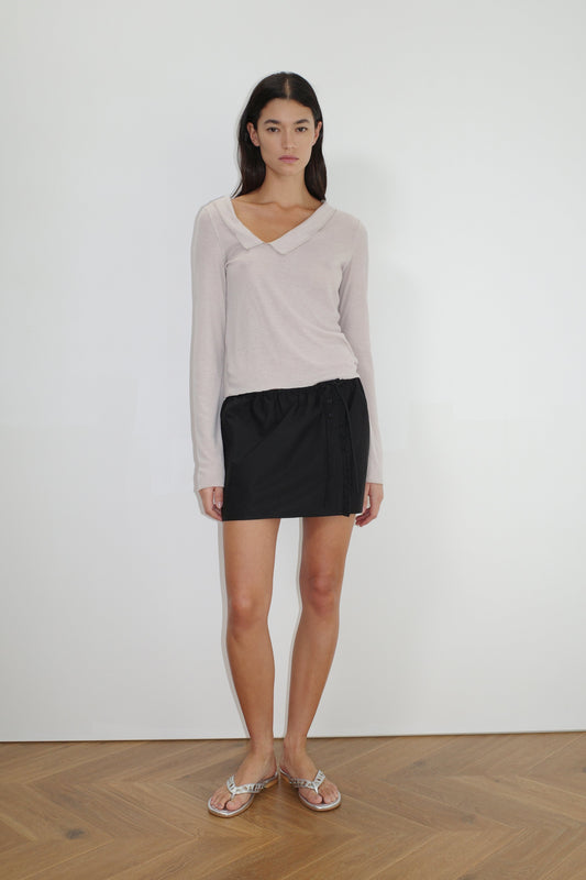 female model wears the ruffle mini skirt by Deiji Studios in black


simple mini skirt designed to sit at low waist features adjustable tie and ruffle edge on side with button detail


made from 100% GOTS certified organic cotton poplin

paired with a sheer knit long sleeve in beige