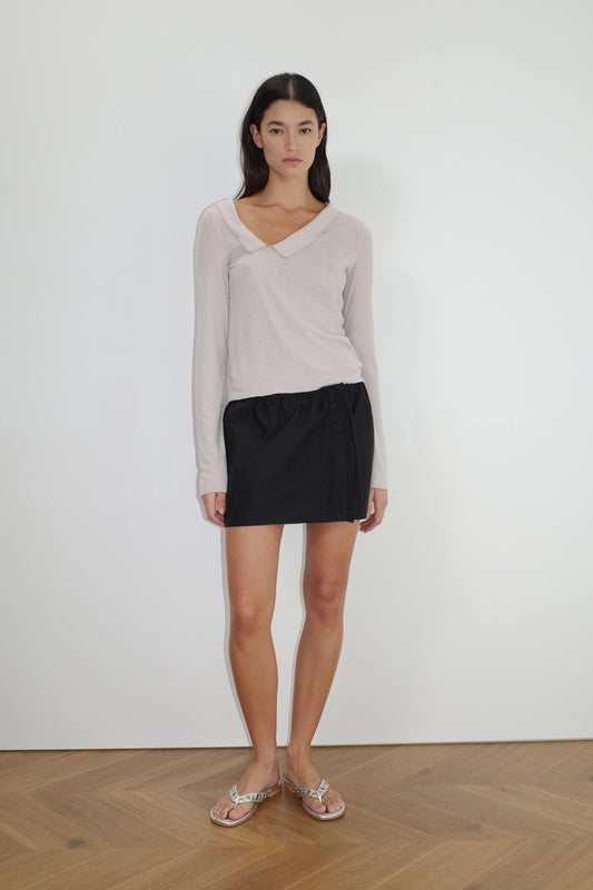 female model wears the ruffle mini skirt by Deiji Studios in black


simple mini skirt designed to sit at low waist features adjustable tie and ruffle edge on side with button detail


made from 100% GOTS certified organic cotton poplin

paired with a sheer knit long sleeve in beige