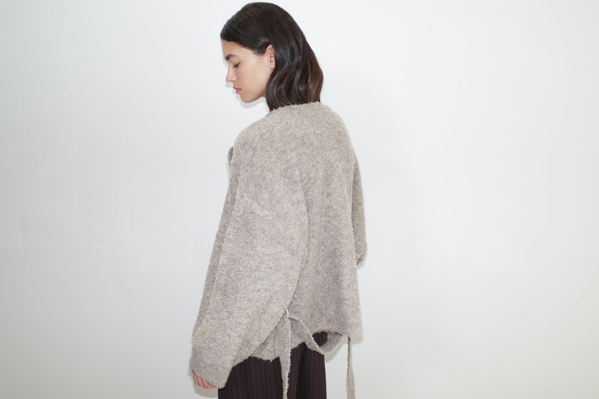 female model wears the pod knit by Deiji Studios in cloud grey


a relaxed and textured knit features a round shaped neckline with press stud front closure, removable self tie belt with long sleeves and high back neckline


made from a sustainable knit blend of 12% RWS certified wool, 30% recycled acrylic, 64% recycled polyester and 4% spandex

paired with a pinstripe wool pant