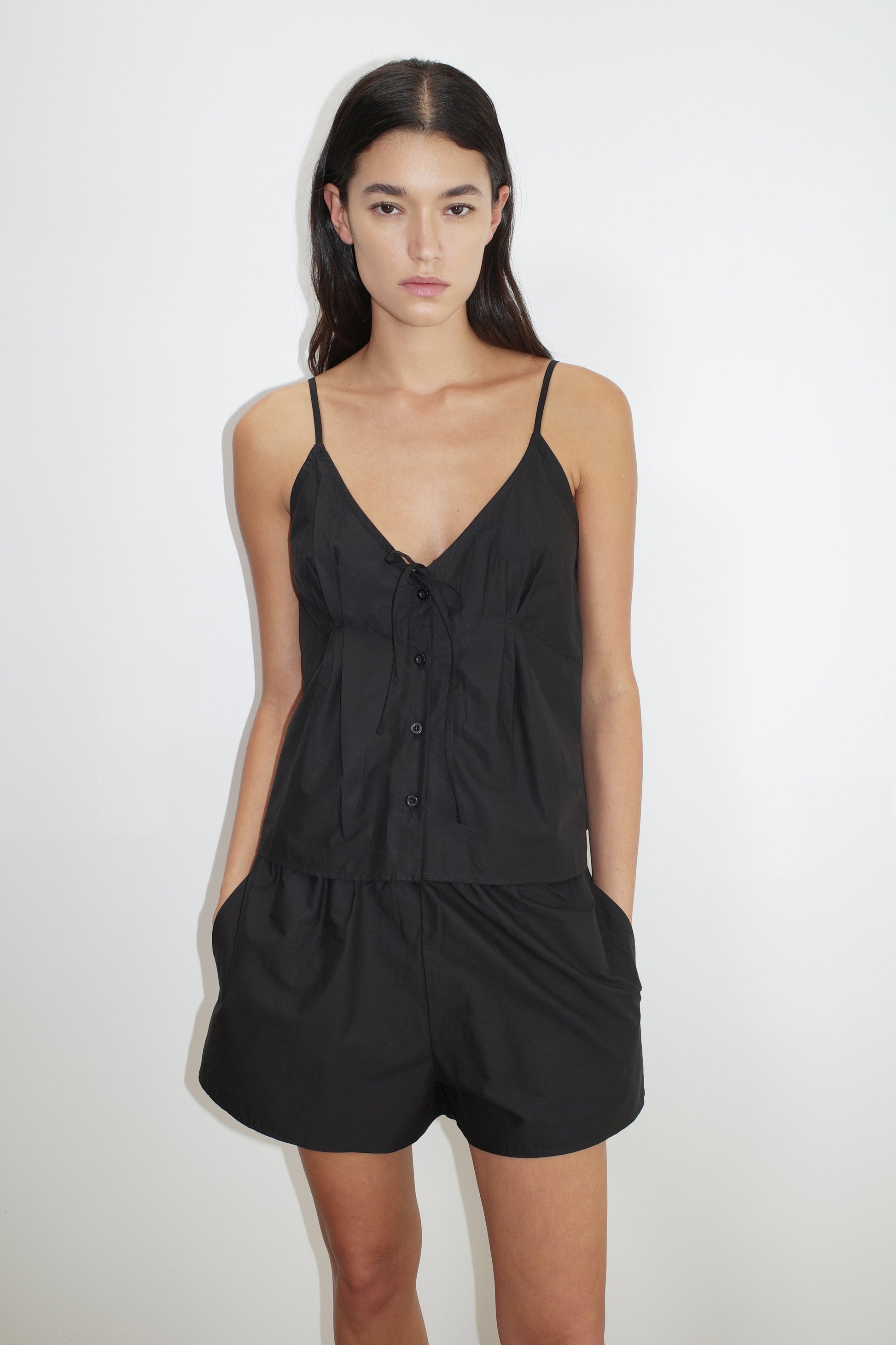 female model wears the placket short set by Deiji Studios in black


a lightweight everyday top features a flattering v neckline, button down front, side fold pleat detail at bust with a self-fabric tie pairs back with an easy pull on short, featuring a soft elastic waist and side seam pockets to wear as a set or separately


made from 100% organic cotton poplin