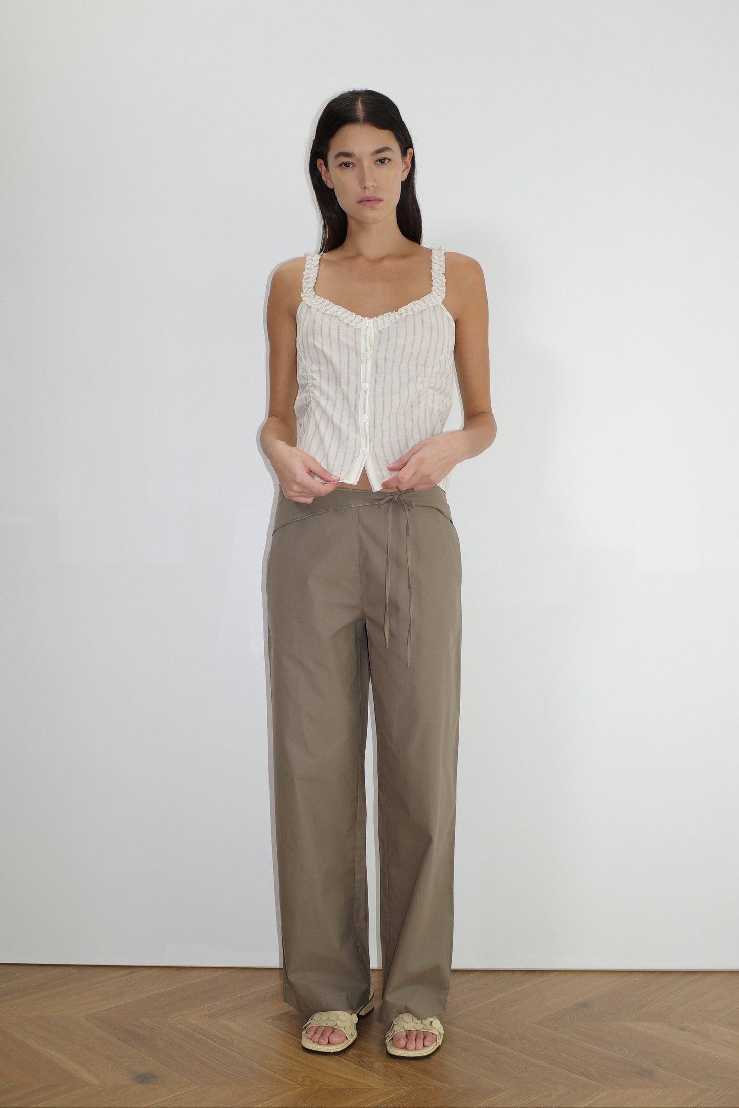 female model wears the ruffle button top by Deiji Studios in raquette stripe


a button up top featuring a butter base with mixed blue stripe, flattering v neckline, self-fabric ruffles along the straps and designed elasticated gatherings


made from 100% GOTS organic cotton

paired with a clay green pant