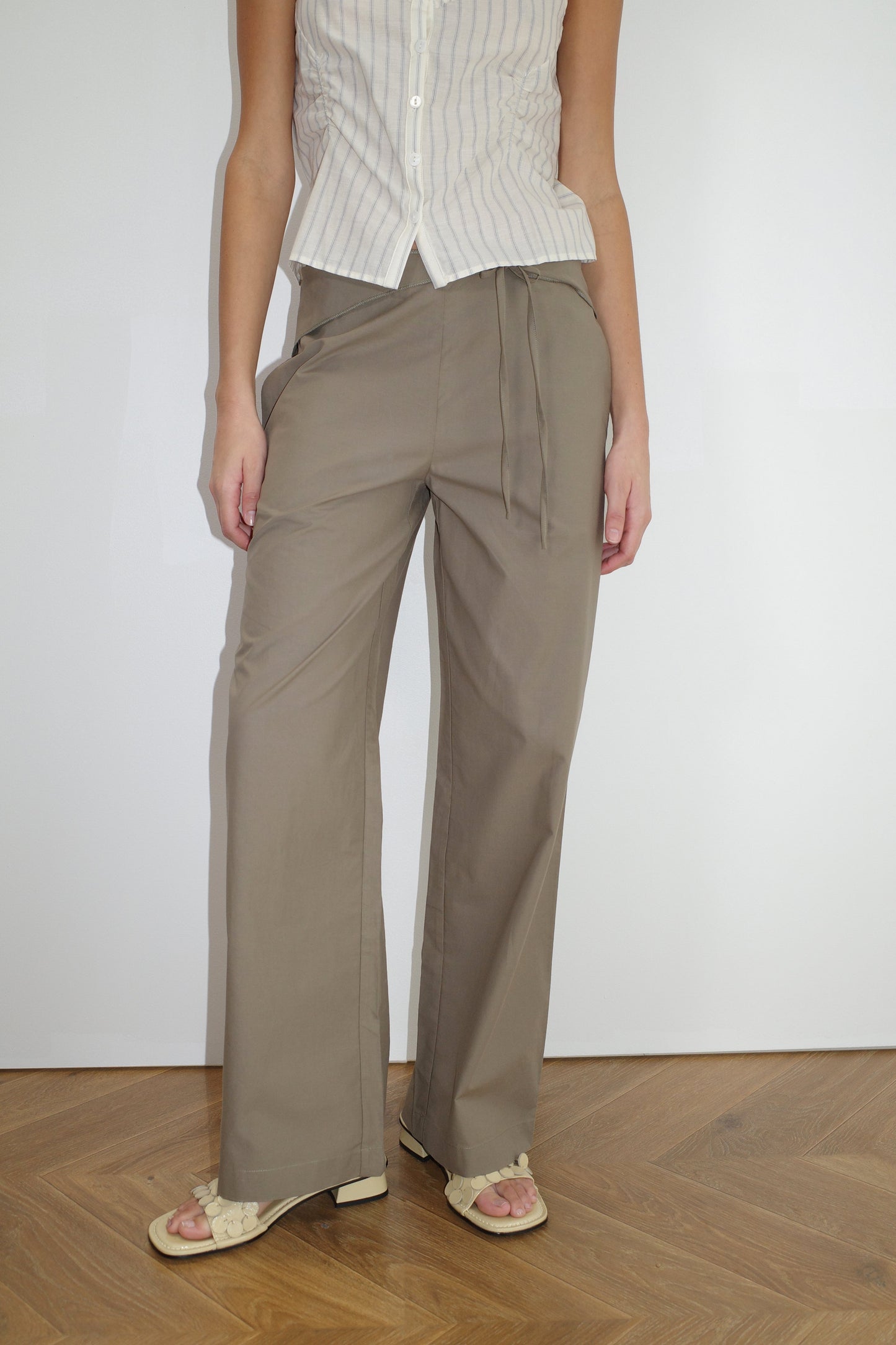 female model wears the belted pant by Deiji Studios in clay


mid-rise loose-leg pant with attached tie-front belt detail, babylock hem, and relaxed fit. features concealed zip closure and side pockets


made from 100% organic cotton

paired with a striped singlet top