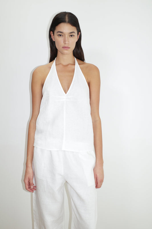 A woman with long dark hair wears the Linen Pinched Halter Top in white with matching pants, standing against a plain white background.