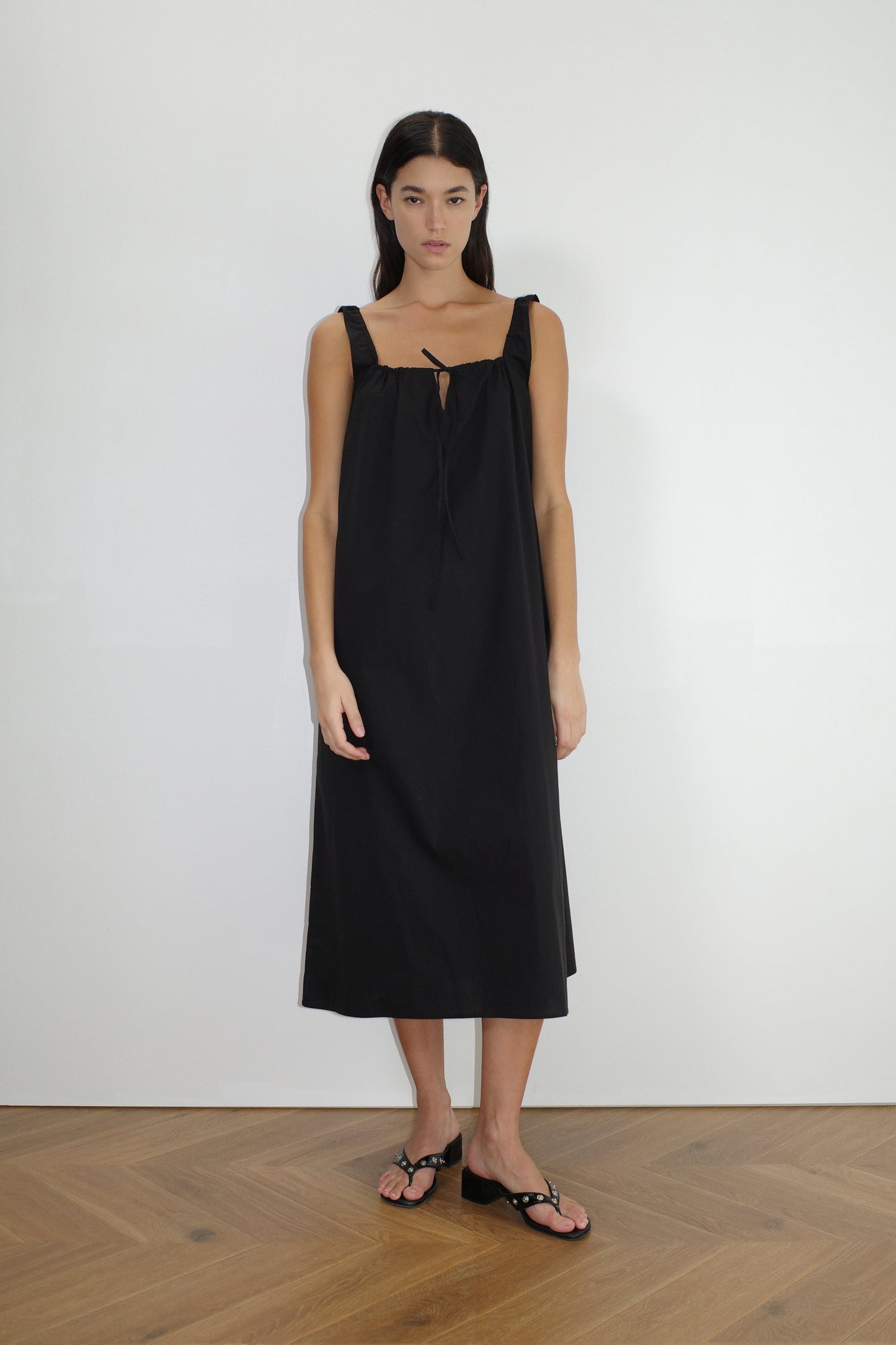 female model wears the paper dress by Deiji Studios in black, a crisp and lightweight maxi-length dress features a flattering gathered square neckline with keyhole and tie front feature and side seam pockets, made from GOTS certified organic cotton poplin