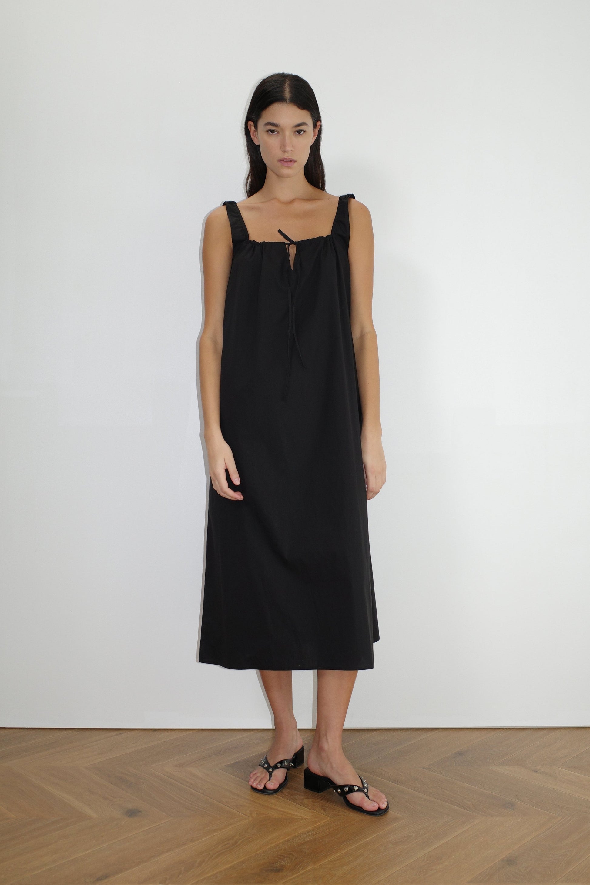female model wears the paper dress by Deiji Studios in black, a crisp and lightweight maxi-length dress features a flattering gathered square neckline with keyhole and tie front feature and side seam pockets, made from GOTS certified organic cotton poplin