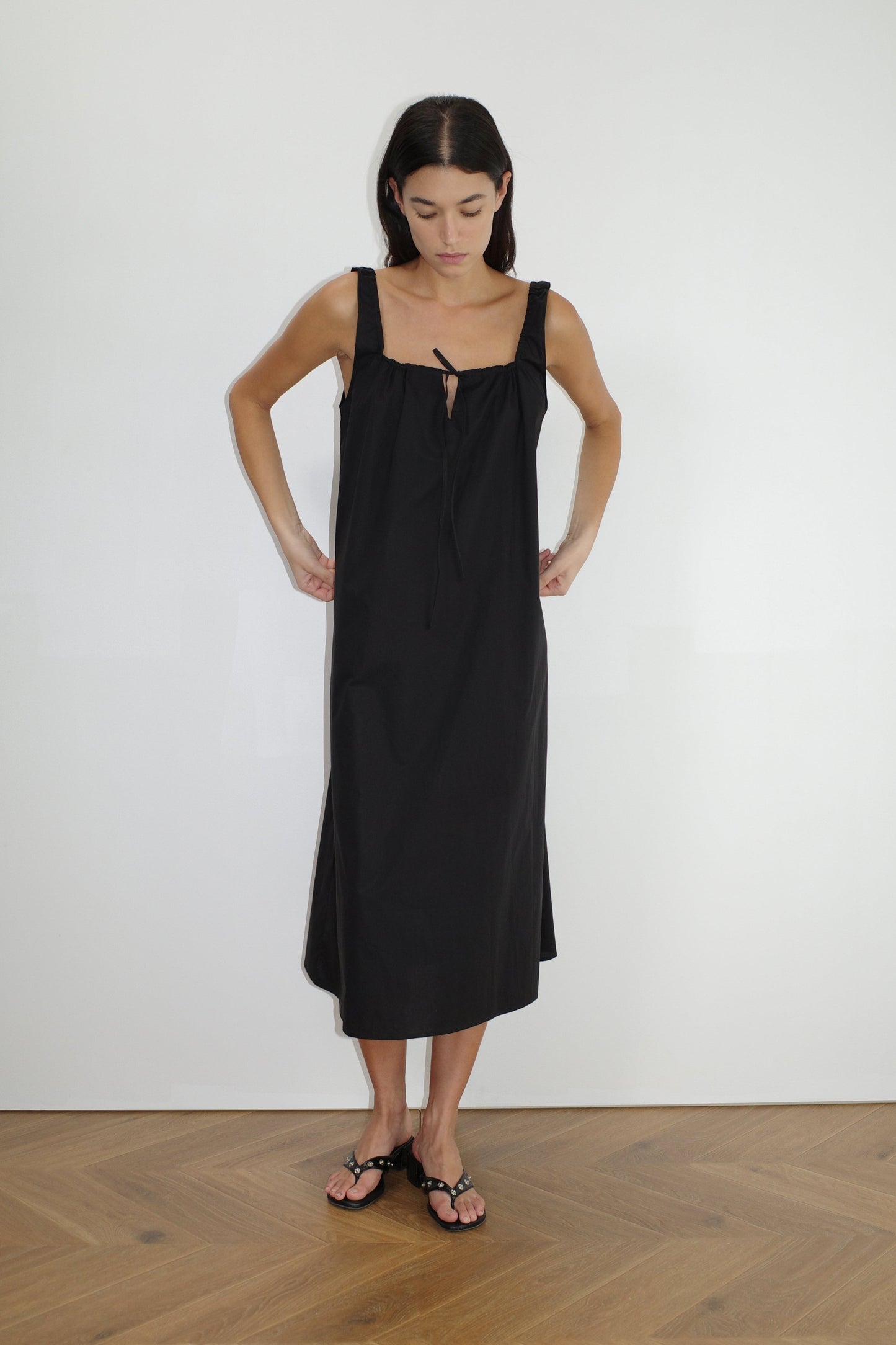 female model wears the paper dress by Deiji Studios in black, a crisp and lightweight maxi-length dress features a flattering gathered square neckline with keyhole and tie front feature and side seam pockets, made from GOTS certified organic cotton poplin
