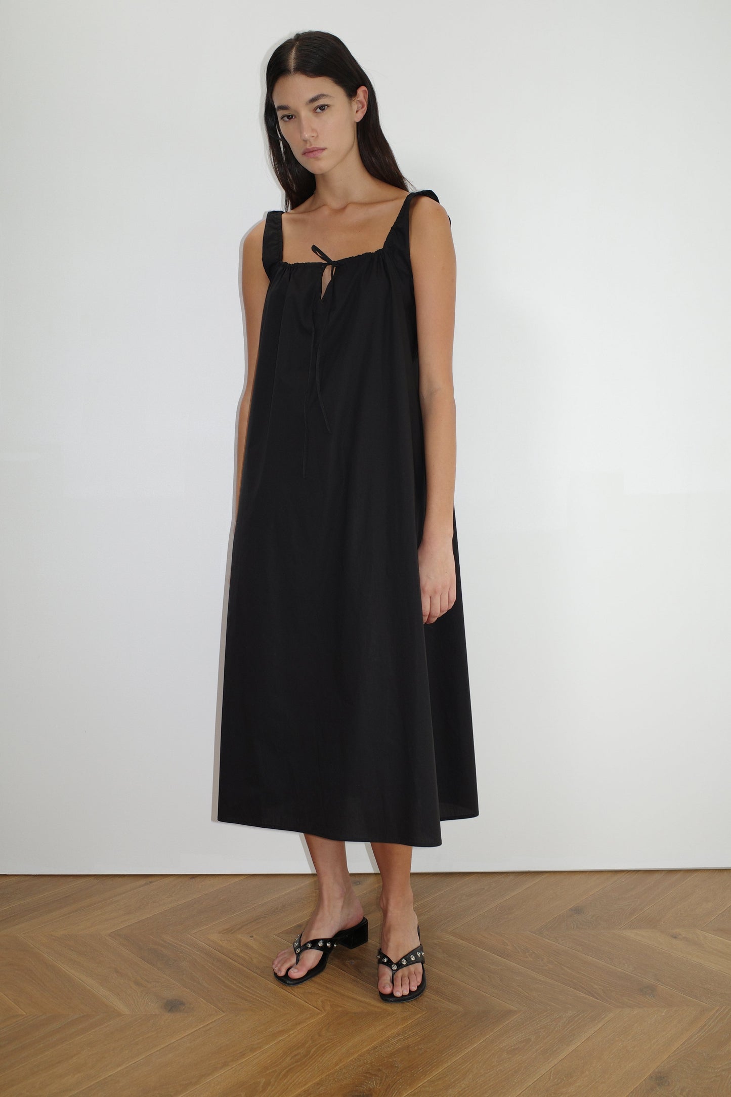 female model wears the paper dress by Deiji Studios in black, a crisp and lightweight maxi-length dress features a flattering gathered square neckline with keyhole and tie front feature and side seam pockets, made from GOTS certified organic cotton poplin