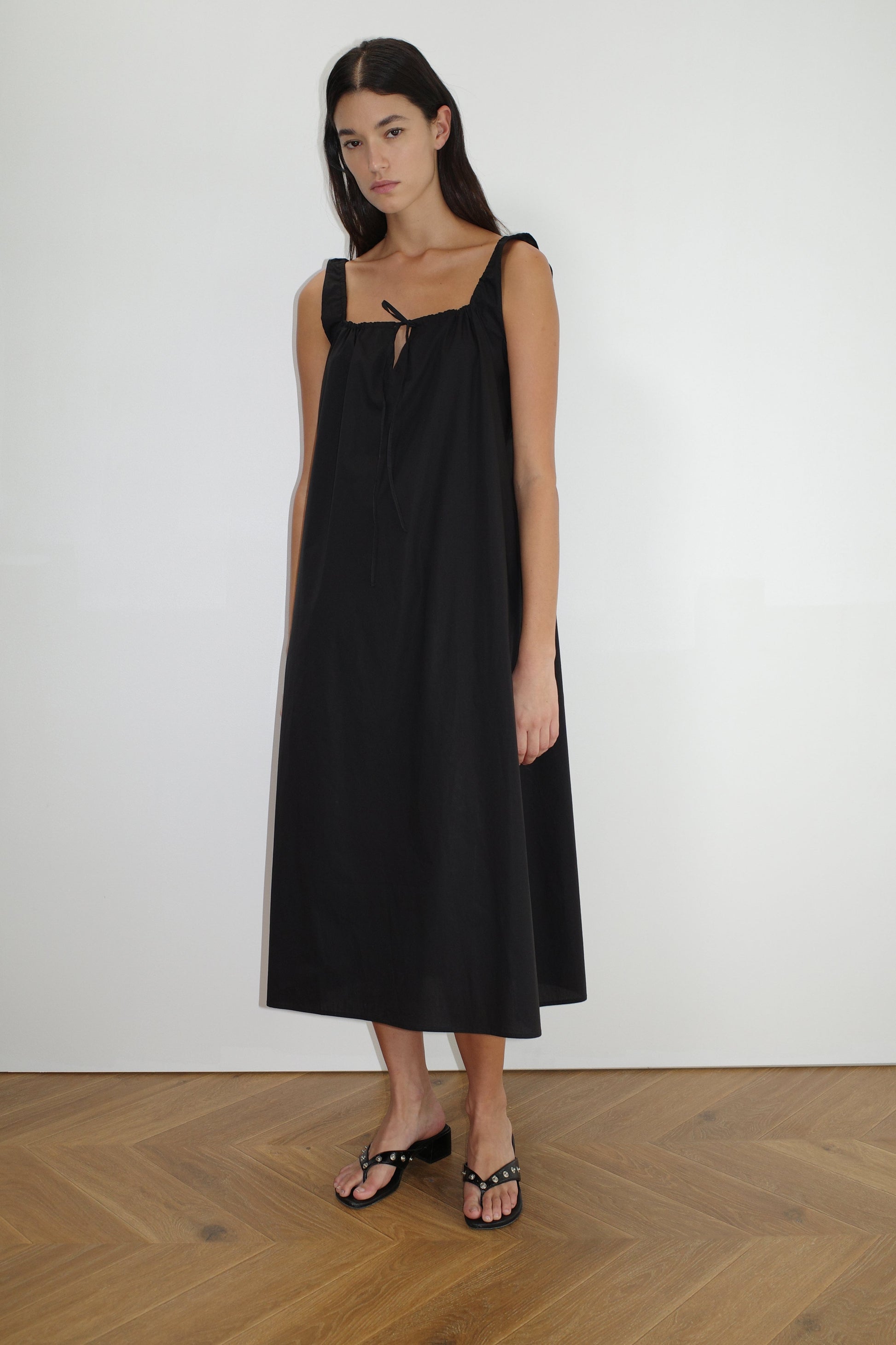 female model wears the paper dress by Deiji Studios in black, a crisp and lightweight maxi-length dress features a flattering gathered square neckline with keyhole and tie front feature and side seam pockets, made from GOTS certified organic cotton poplin