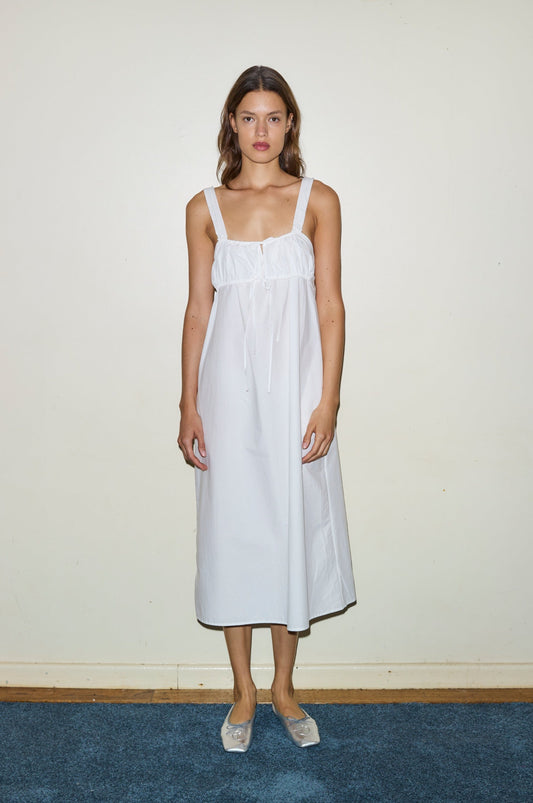 Female model wearing The Ruched Tie Dress - White by Deiji Studios against plain background