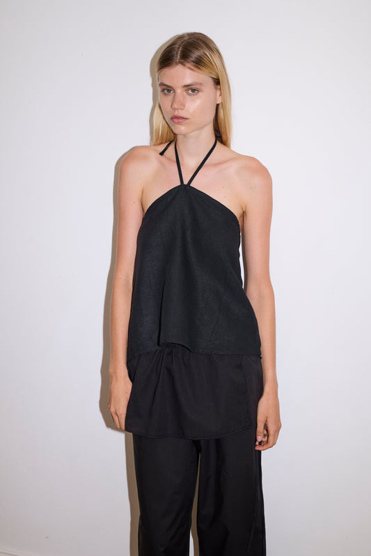 blonde haired female model wears a black relaxed halter top features flattering straight neckline, fine tie halter straps and snap closure at back with button detail, paired with a black ankle length pant features a soft minimal elastic waist with side seam pockets in a straight leg.