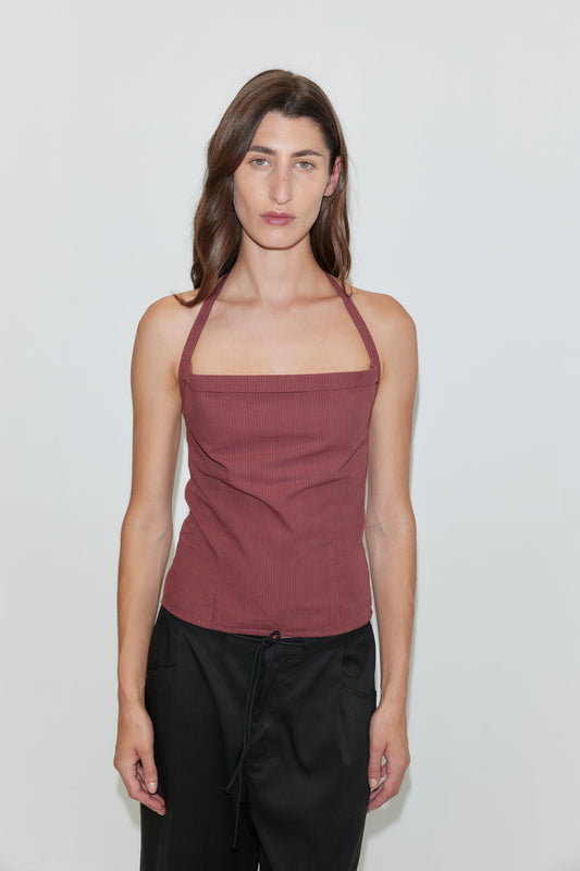 A woman with long brown hair wears the Folded Top - Rust Stripe, paired with black pants, standing against a plain white background and looking directly at the camera with a neutral expression.