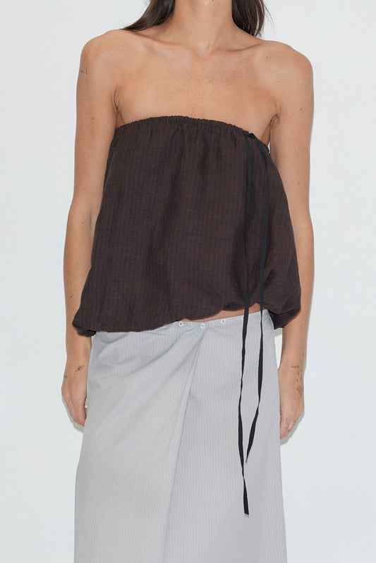 A cropped shot of the Bubble Top - Brown Black Stripe by Deiji Studios, a strapless dark brown striped linen top with an elasticated top edge, contrast black grosgrain drawcord tie and fully lined bubble hem, worn with a light grey striped wrap skirt against a plain white background.