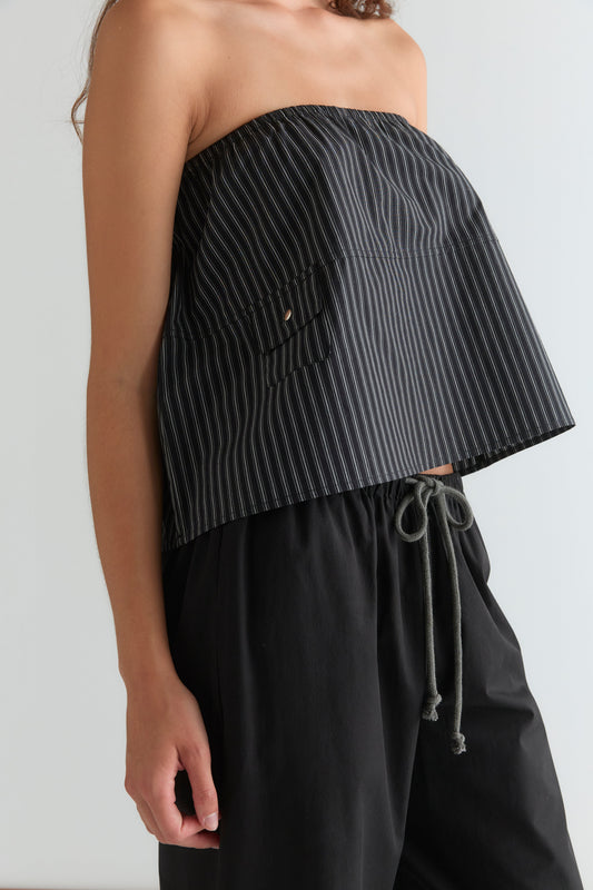 A person wears a strapless, black and white pinstriped top with the Pocket Skirt - Mono Stripe, featuring an elasticated waistband, against a plain light background.