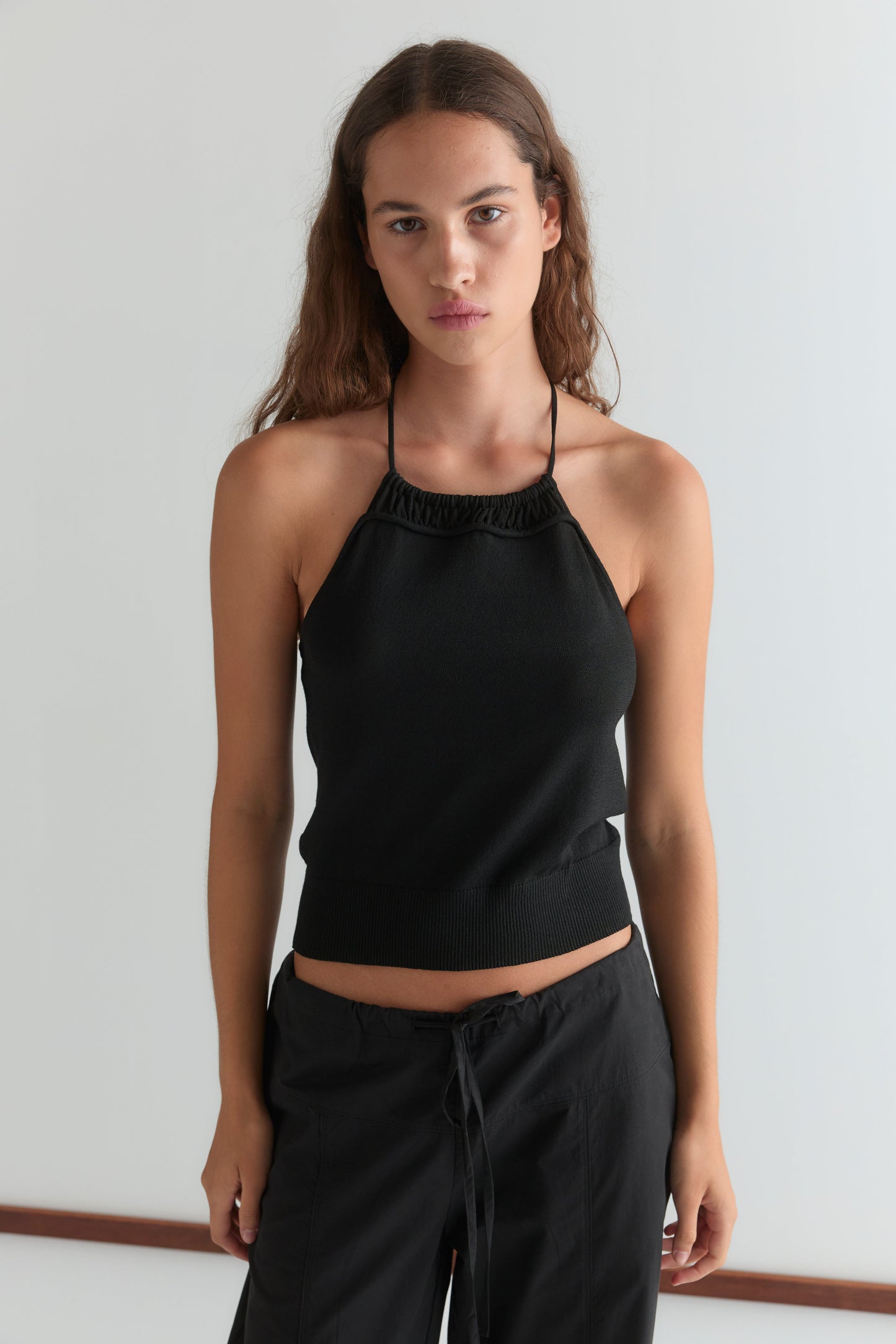 A woman with long brown hair models the Drawcord Knit Top and black drawstring pants, standing against a plain white background and looking directly at the camera with a neutral expression.
