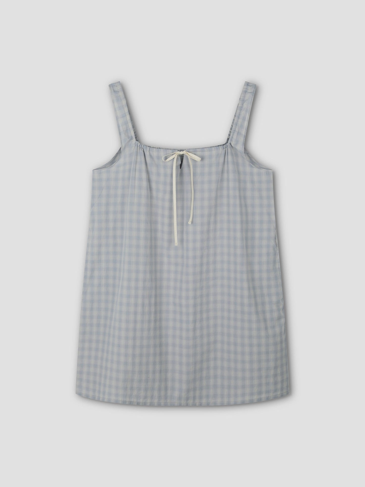 The bow dress - blue check: A sleeveless, mini-length dress with wide shoulder straps and a cream bow tie at the neckline, displayed flat on a light gray background.