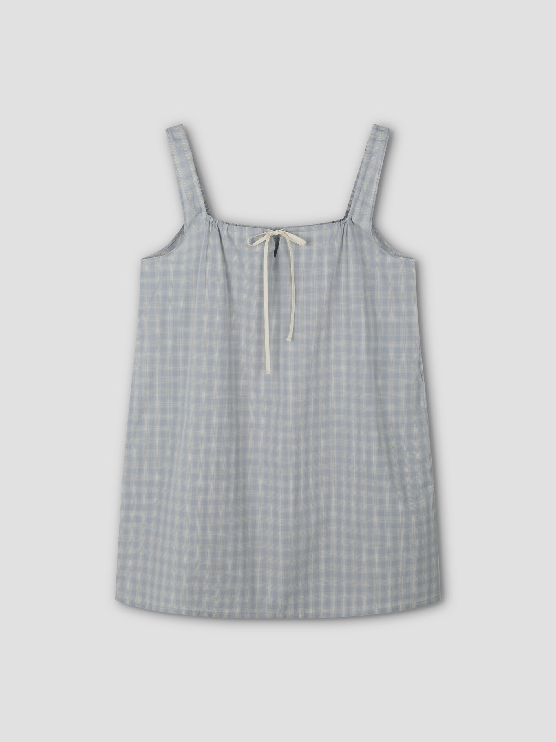 The bow dress - blue check: A sleeveless, mini-length dress with wide shoulder straps and a cream bow tie at the neckline, displayed flat on a light gray background.