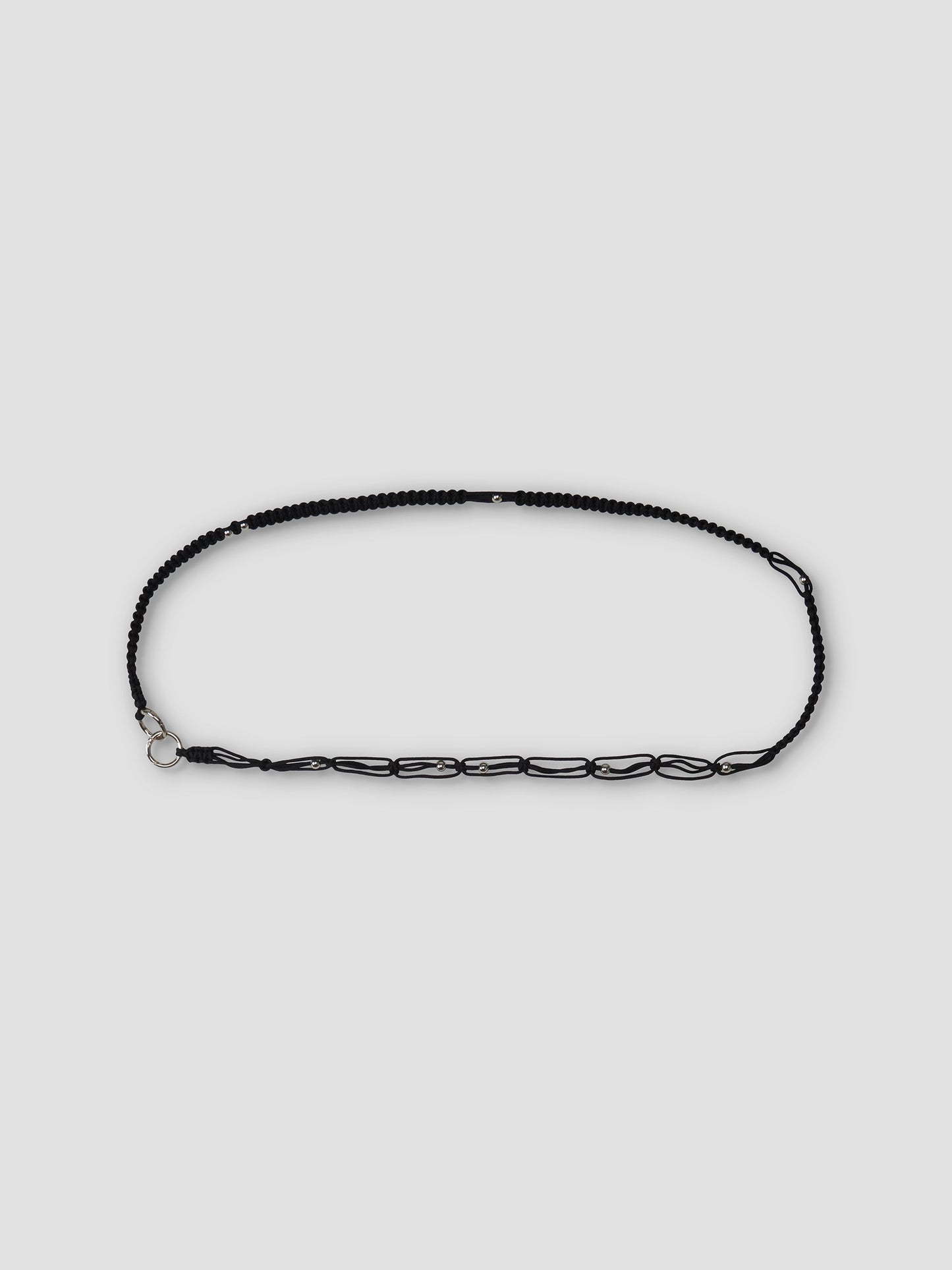 The O Ring Belt - Black features black beads and chain, an adjustable carabiner closure, and a silver clasp, displayed in an oval shape on a plain light gray background.