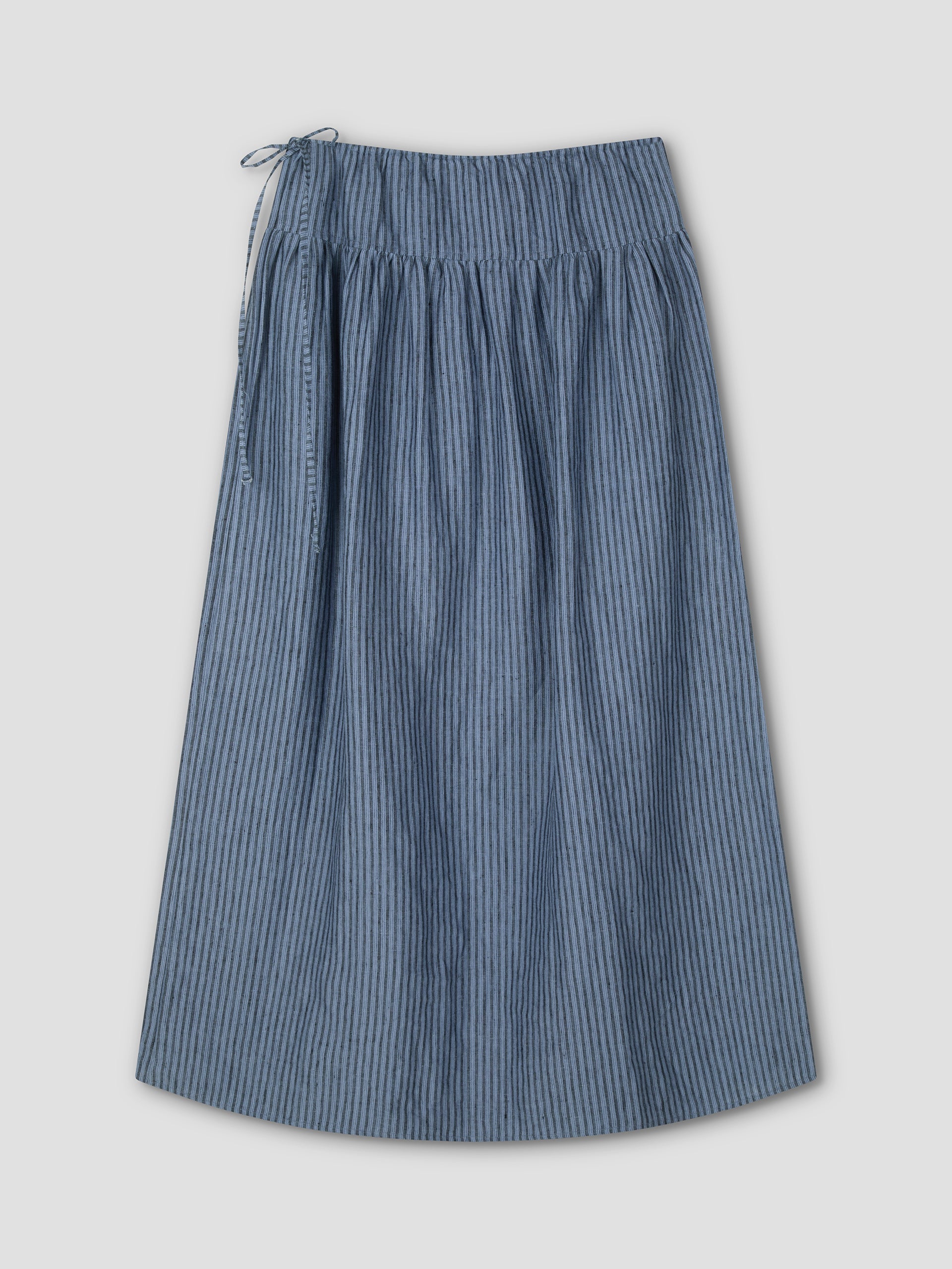 The Maxi Skirt - Azure Stripe is a knee-length, blue and white striped skirt featuring a gathered waist and left-side tie, shown on a plain light grey background.