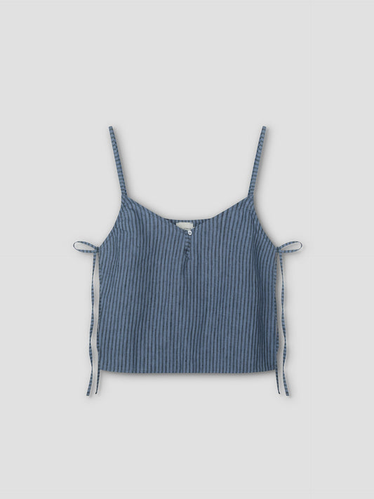 The V Neck Cami - Azure Stripe is a sleeveless crop top with thin shoulder straps, a front button, and side ties. Made from lightweight textured fabric for a relaxed feel, it features an azure stripe pattern on a light grey background.