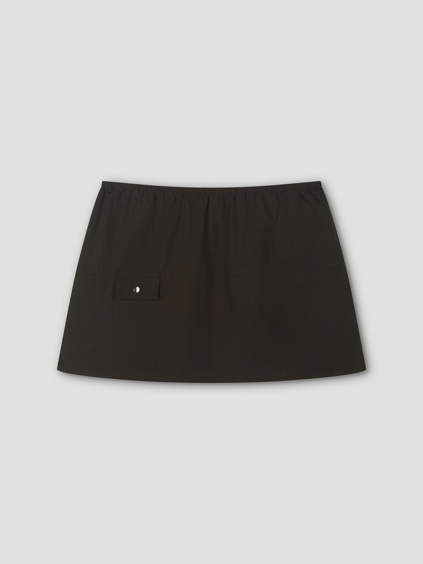The Pocket Skirt is a plain black mini skirt with an elastic waistband and a small flap pocket with a button on the left side, shown on a light gray background.